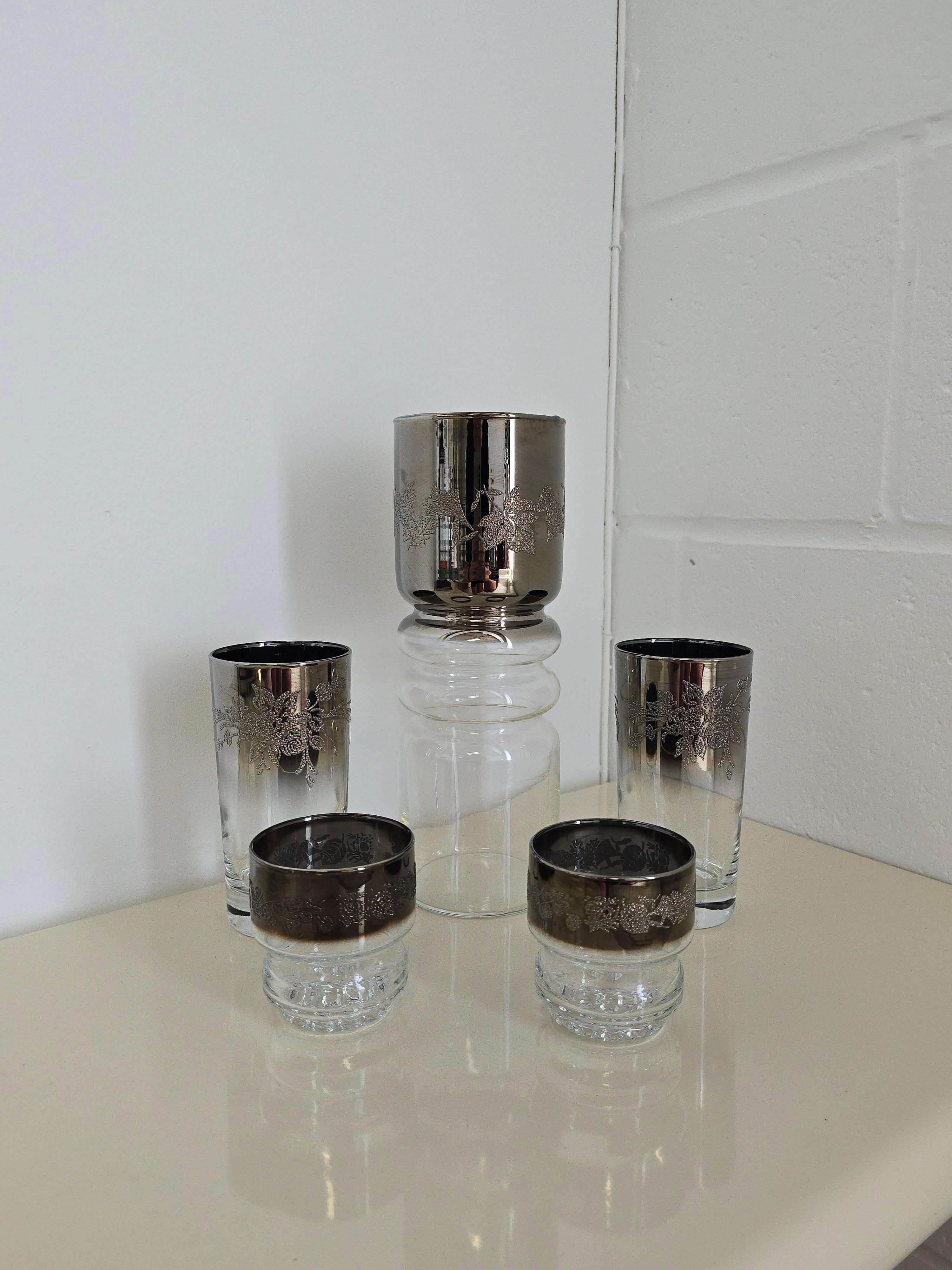 A set of Thorothy Thorpe 1960s midcentury modern Glassware. The set includes one large Pitcher and four glasses. The four glasses are two large glass and two small glass. There's a gorgeous silver detailing on the rims of the glasses. The silver