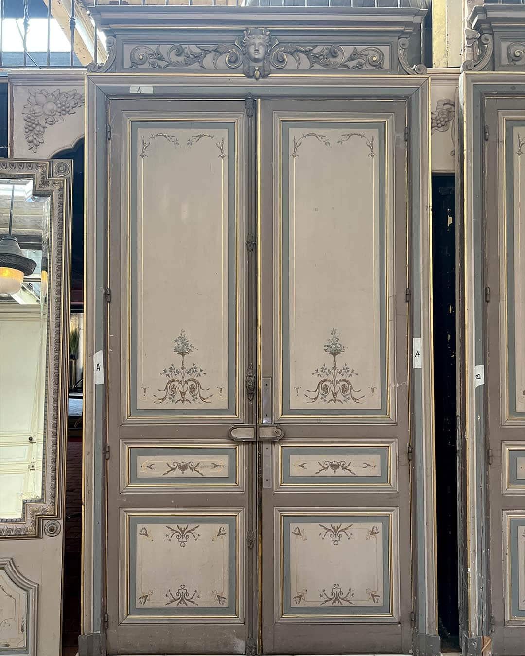 Prächtiger Satz von drei Doppeltüren mit originalen Rahmen und Sprossen, reich verziert im neoklassizistischen Stil. Jede Tür weist handbemalte Paneele mit floralen Motiven, vergoldeten Akzenten und geschnitzten Giebeln auf, die von geschnitzten