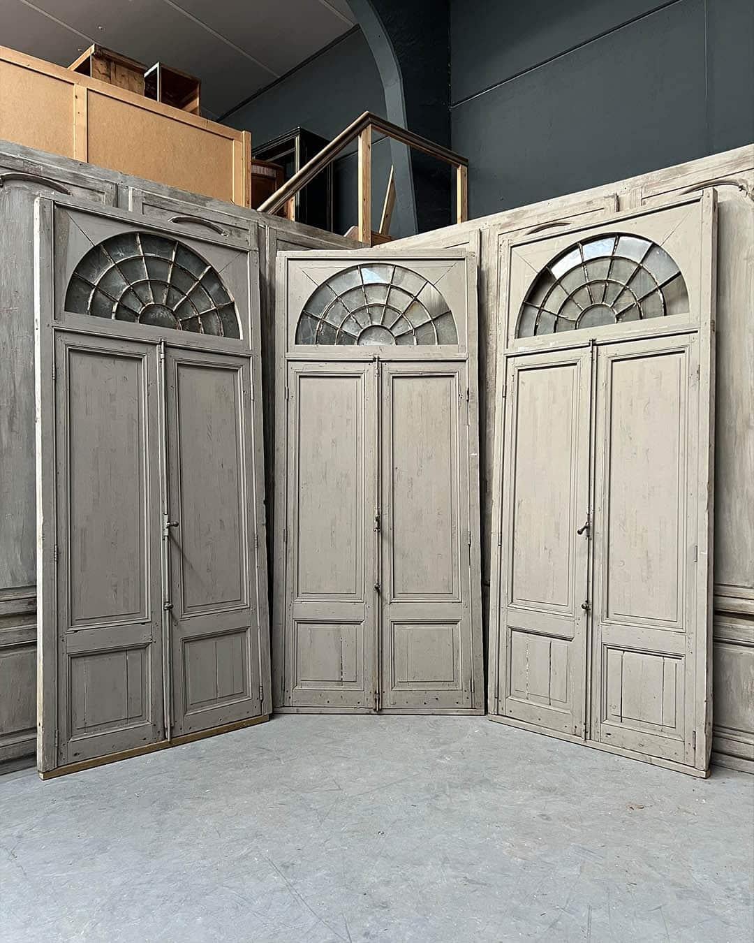 Elegante serie di tre porte a doppia orangerie con cornici originali e traversi ad arco con sopraluce. Questo raro insieme mette in mostra una bellezza architettonica senza tempo e un'autentica maestria. I traversi in vetro antico permettono alla