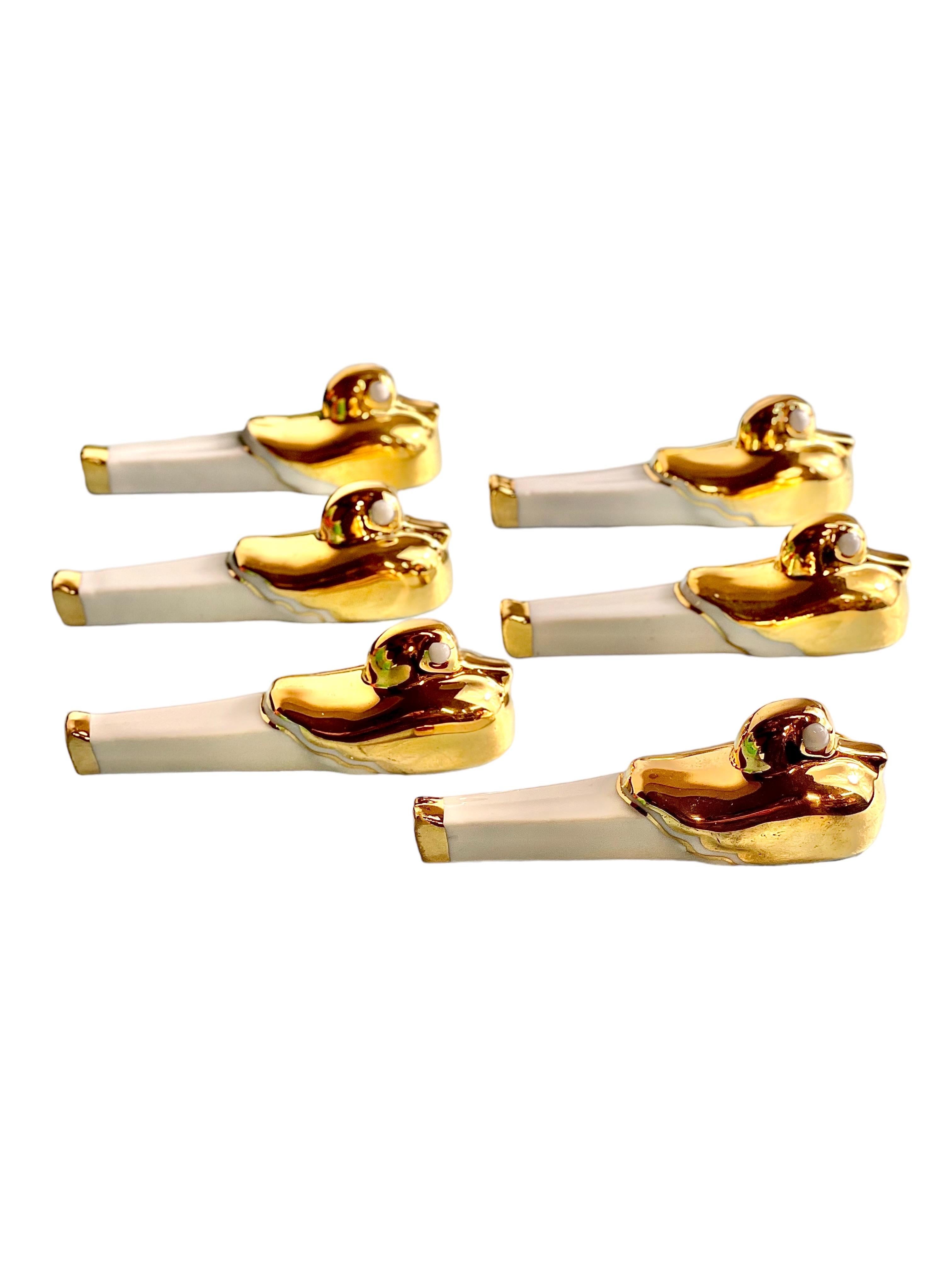 An unusual and very charming table set consisting of six Art-Deco style duck-shaped porcelain knife rests, and two small salt cellars with their original tiny spoons. Hand-crafted from gleaming, gold-plated white porcelain, this set was made by the
