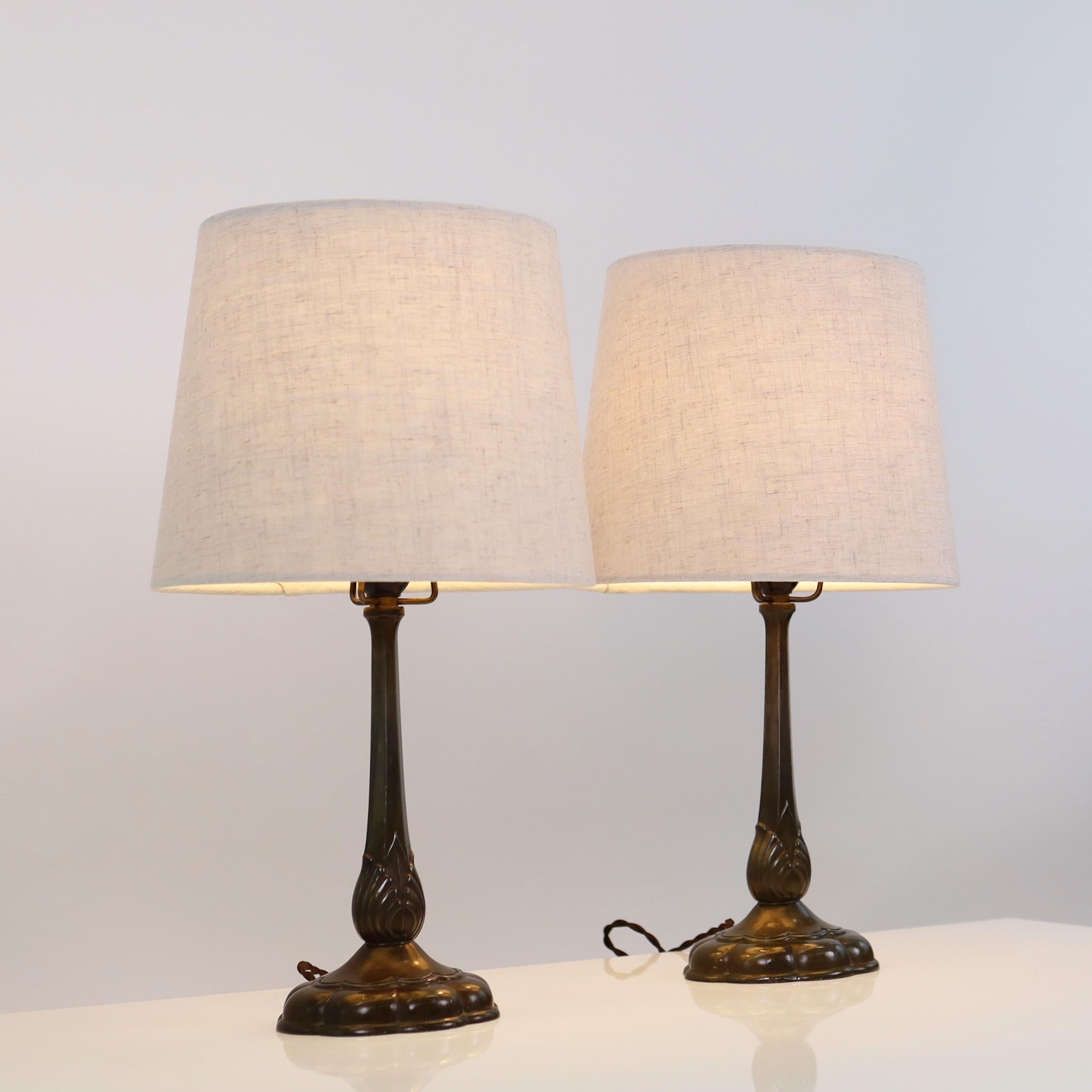 A set of early Just Andersen table lamps made in the 1920s. A rare set in good vintage condition closing in on a 100 years of life-time.

* A set (2) of metal desk lamps with vertical lines on an flower-shaped foot with ornaments and beige fabric
