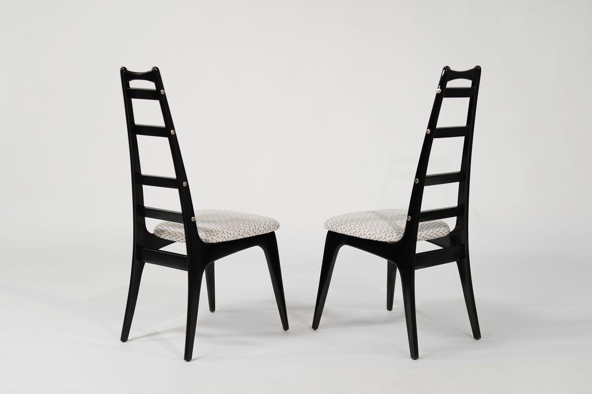 Questo set di sedie vintage con schienale a scaletta è stato meticolosamente restaurato dagli esperti artigiani di Stamford Modern. Ogni sedia è stata ebanizzata di recente, rivelando una finitura ricca e lucente che contrasta magnificamente con gli