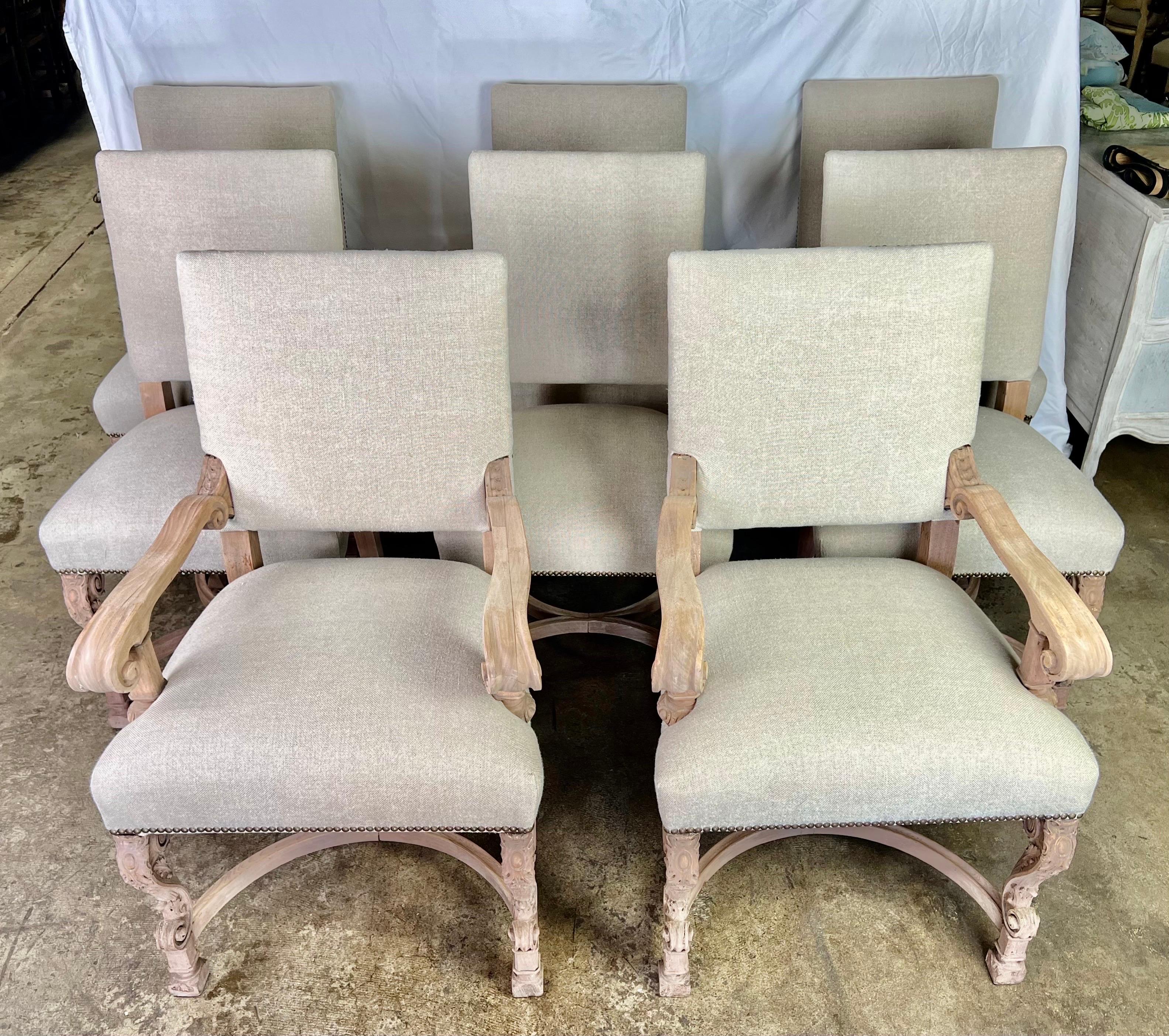 Set of Eight French bleached mahogany dining chairs. The chairs stand on four carved cabriole legs with rams head feet. The chairs are newly upholstered in a washed Belgium linen textile.
