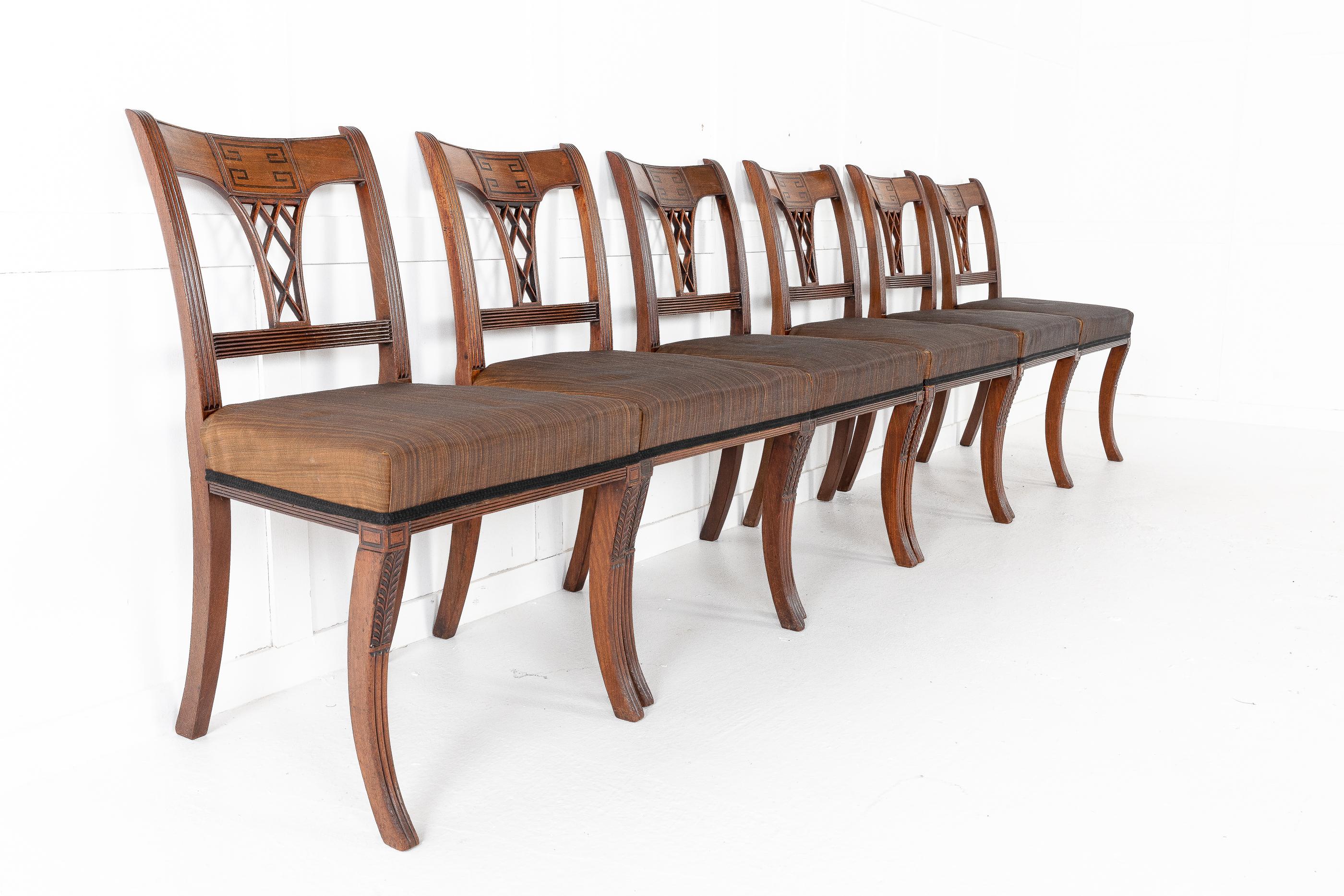 Set of eight, 19th century Regency mahogany dining chairs. Having a shaped top rail with an ebony inlaid Greek key pattern, reeded frames on sabre legs, with carved leaf pattern. Pierced trellis back splats and the seats retaining old horse hair