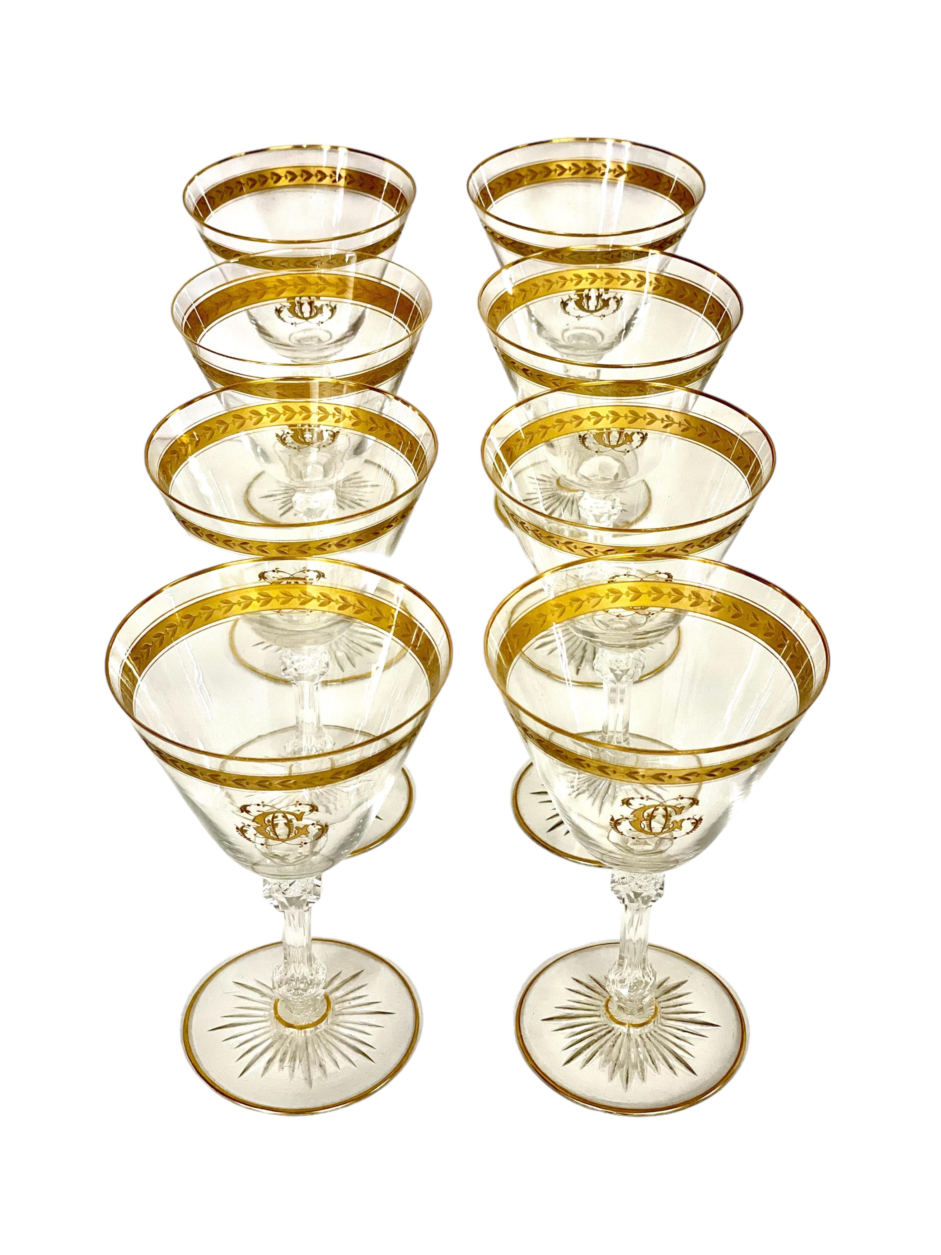 Elegante juego de ocho copas de vino de cristal del siglo XIX, cada una de ellas generosamente adornada con un borde dorado y una banda superior de hojas de laurel doradas, y con un elaborado monograma 