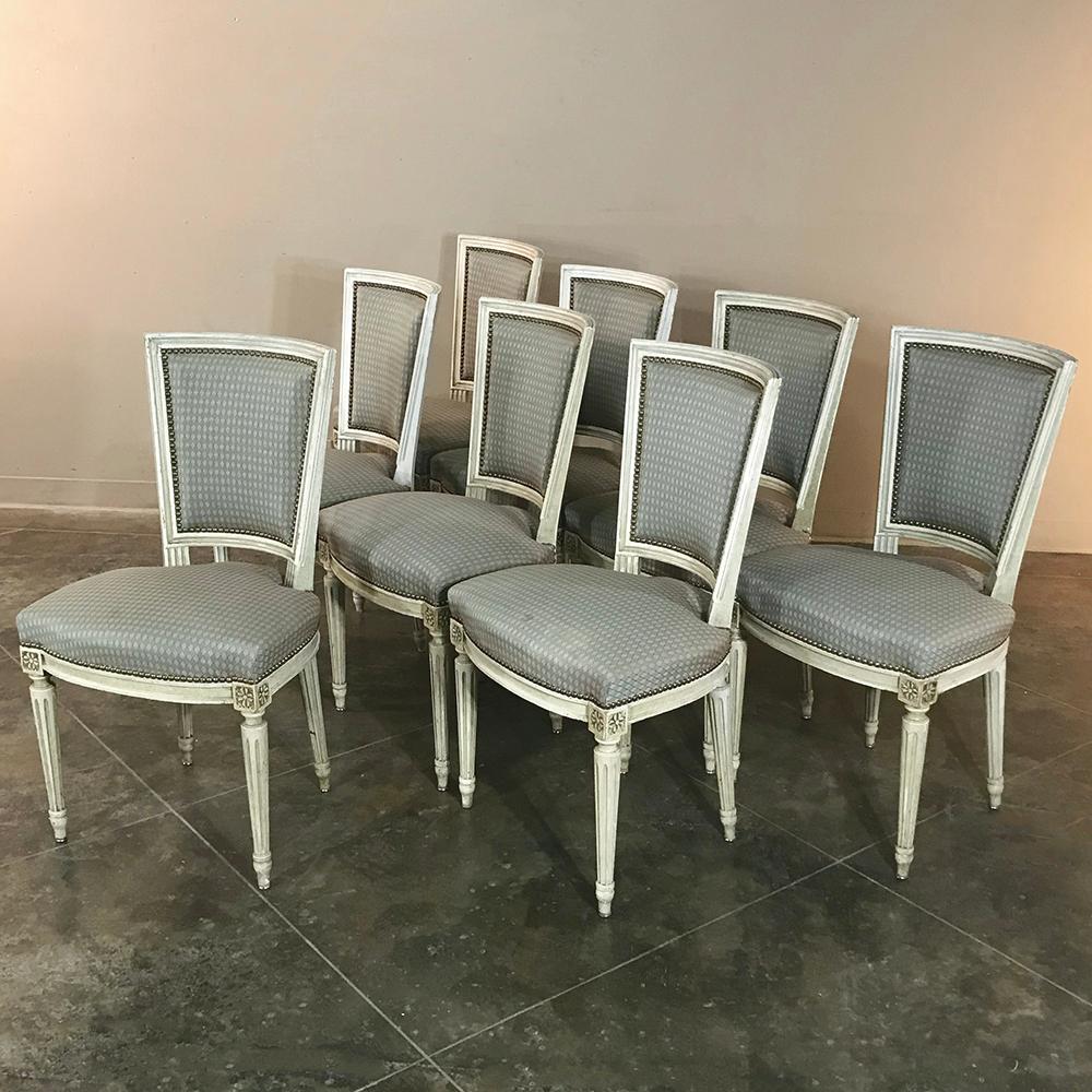 Set of eight antique French Louis XVI dining painted chairs combine comfort with tailored style, and feature contoured seatbacks, spacious seats, and a patinaed painted finish on the framework. Rosettes and tapered and fluted legs provide visual