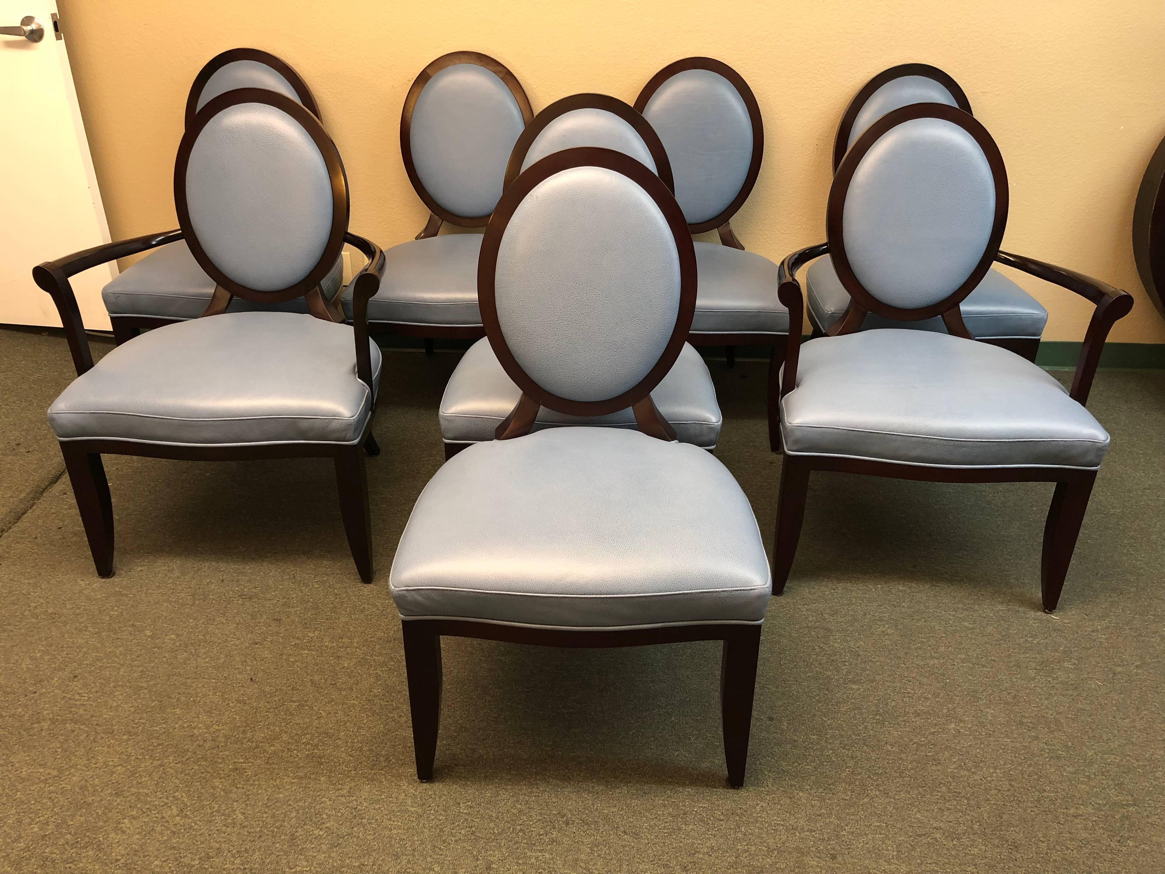 A set of eight dining chairs. Bearing the signature Barbara Barry X-back, the oval dining chair features a refined mahogany wood frame and inset back upholstered in a beautiful corn flower blue leather. There are two armchairs and six sides. Side