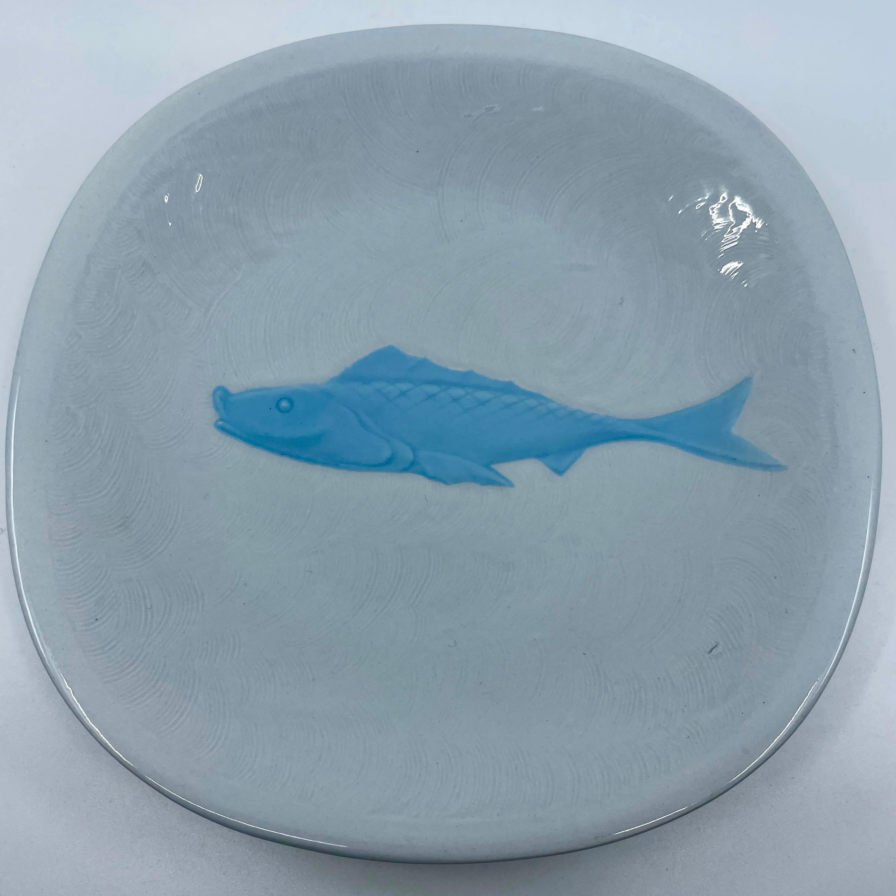 Set of eight blue and white majolica fish plates. Pale blue and white ceramic plates featuring raised center fish in icy blue, surrounded by combed wave pattern with markings for Galvani Ceramiche. Italy, 1930's.
Dimensions: 9.5