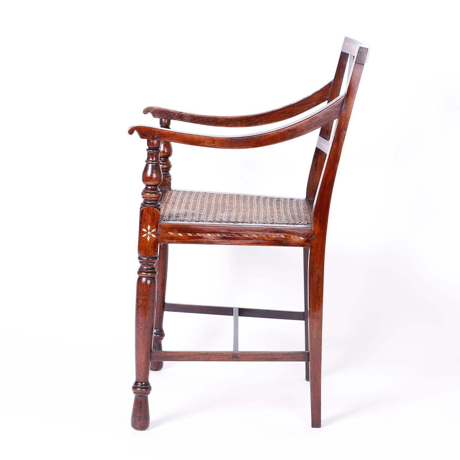 Set of eight British colonial armchairs crafted in mahogany featuring floral bone inlays, pegged construction, caned seats and turned front arm supports and legs. These chairs are excellent examples of the Philippine school of cabinetmaking, with