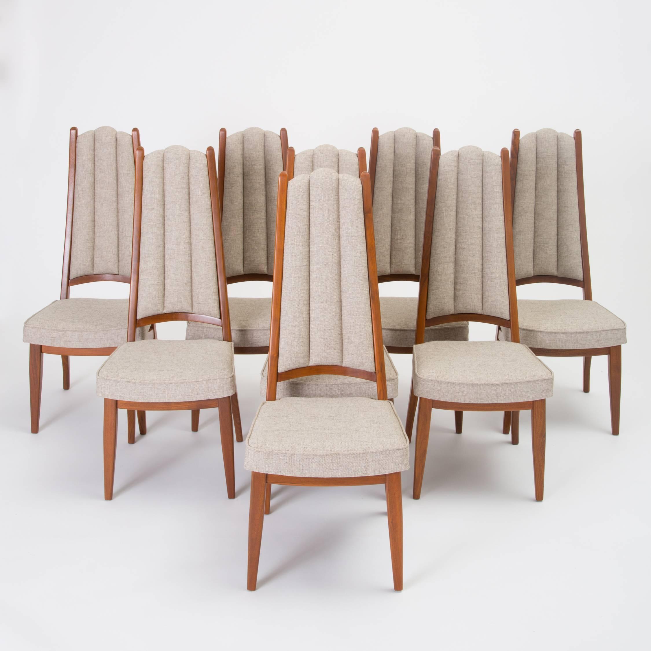 Eight high-backed dining chairs by Cal-Mode, a short-lived Culver City, Los Angeles-based manufacturer. Each chair has a solid walnut frame with angled legs and a backrest defined by two wooden finials and channel-tufted backrests. Each chair bears