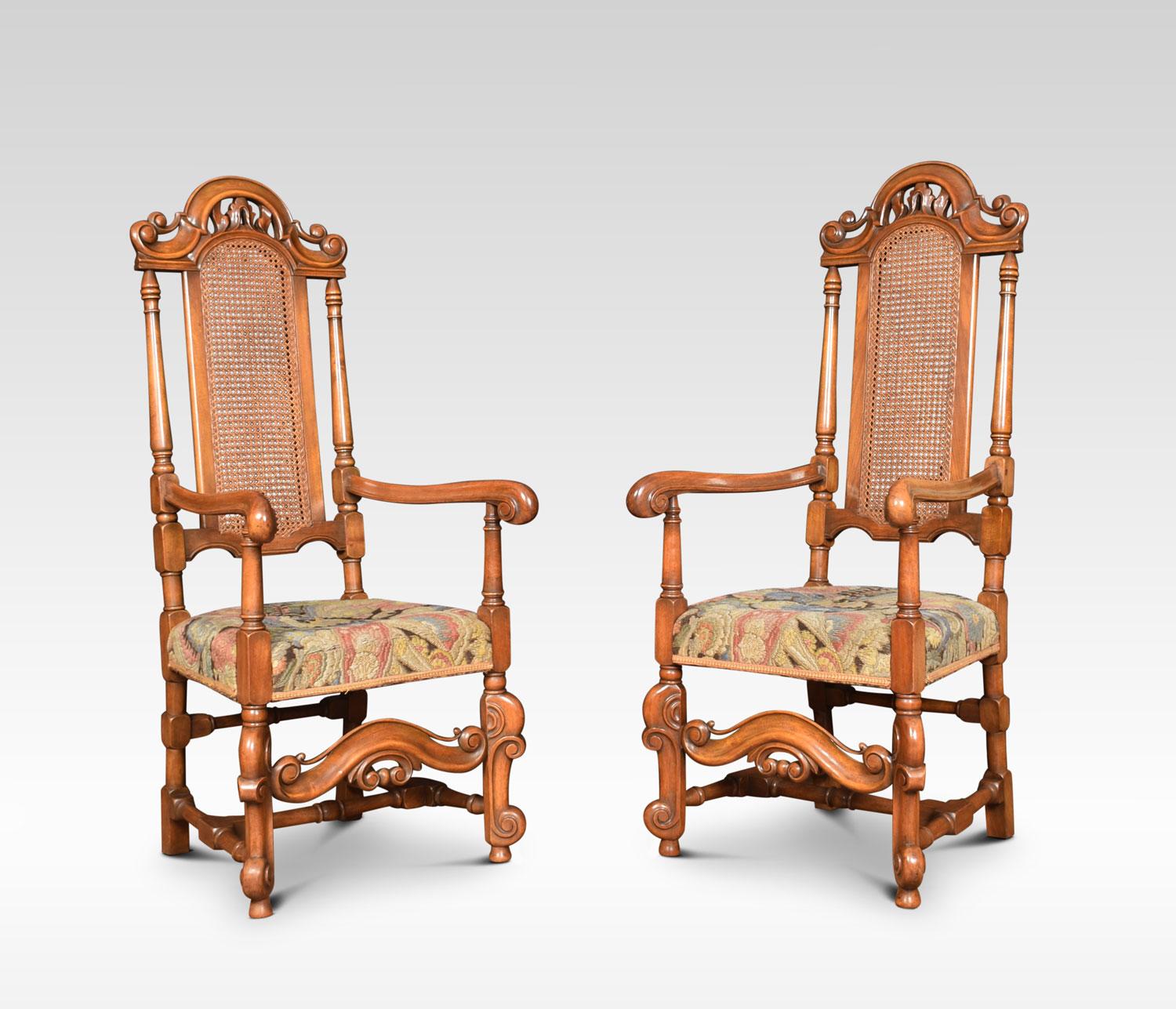Set of eight Carolean style high back dining chairs. Comprising of two armchairs and six chairs, with scrolling crests above arched caned backs and overstuffed needlepoint seats. Raised up on turned scrolling supports united by