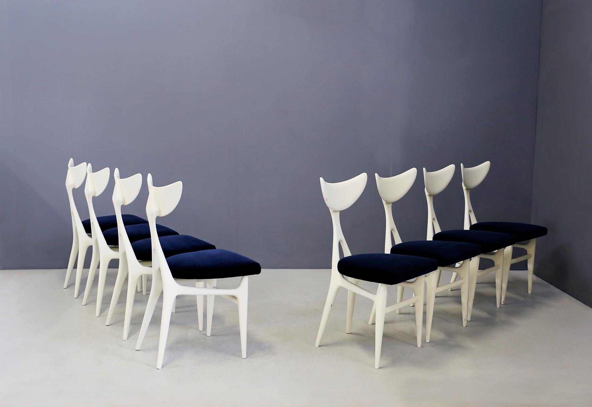 Sculptural set of eight Italian chairs designed by architects Ennio Canino and Viviana Rizzi for Arredamenti Roma, 1954. The set is made of mahogany white paint. Its seat is again lined in blue velvet. The chairs have an anthropomorphic shape almost