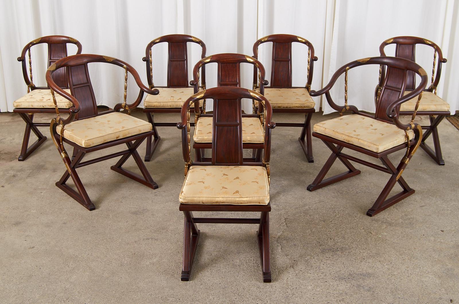 Dramatic set of eight carved hardwood Chinese export dining armchairs made in the Ming dynasty style. The chairs feature a hand-carved hardwood frame with a horseshoe shaped chair rail ending with scrolls. The arm supports gracefully curve down to a