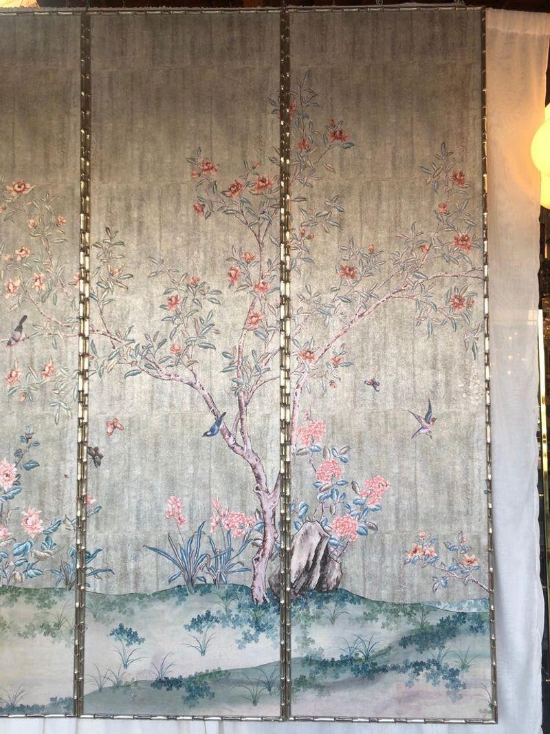 Set of eight Chinese inspired panels with silver leafed faux bamboo frames. The panels are of a landscape with cherry blossoms and birds. A single panel measures: 96 inches H x 21.5 inches W x 1 D.