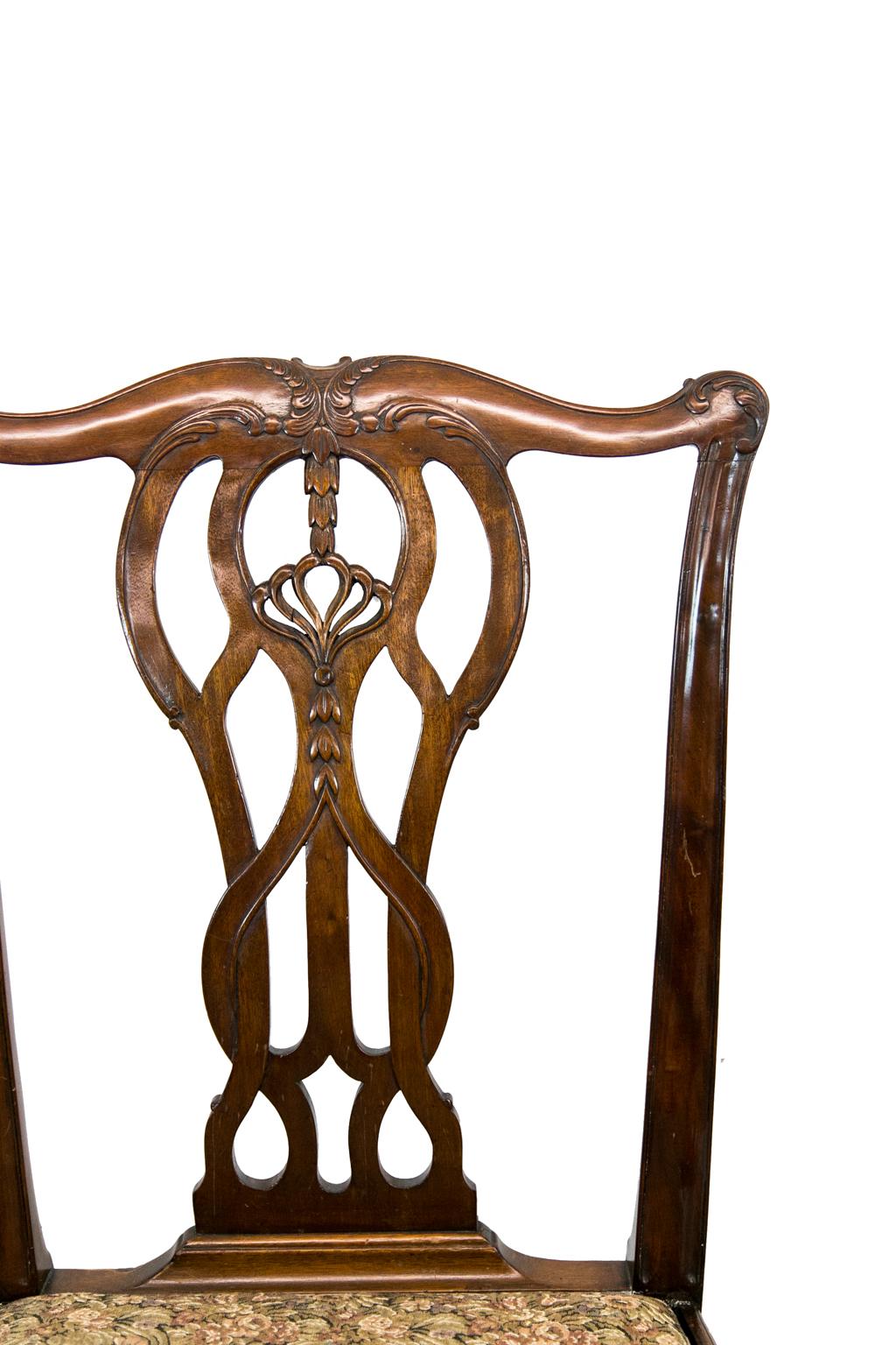 Ensemble de huit chaises de style Chippendale, avec deux bras et six côtés. Elles sont sculptées d'éclisses entrelacées avec des sculptures de clochettes graduées dans une crête stylisée de feuilles d'acanthe. Les pieds sont sculptés de feuilles