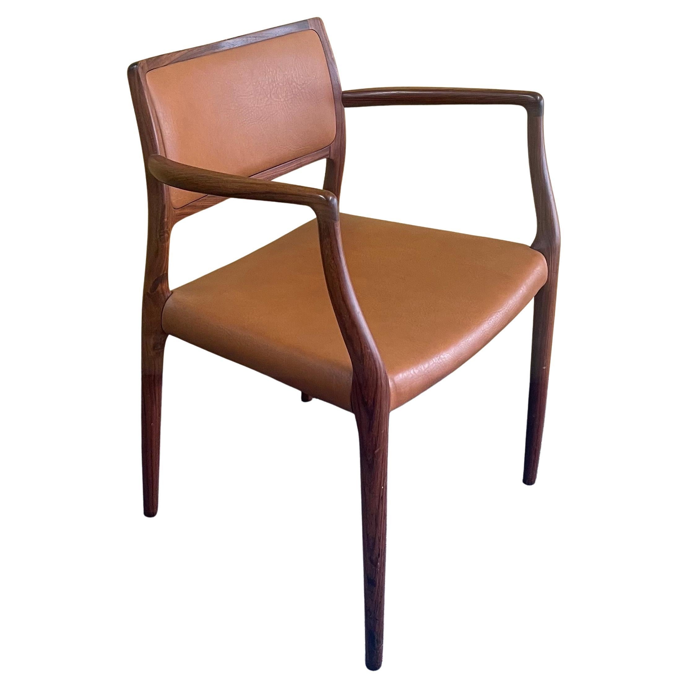 A very nice set of eight model #65 rosewood dining arm chairs designed by Nils Moller, circa 1960s. The chairs are solid rosewood construction with the original brown leather upholstered seats. The set is in very good vintage condition and each