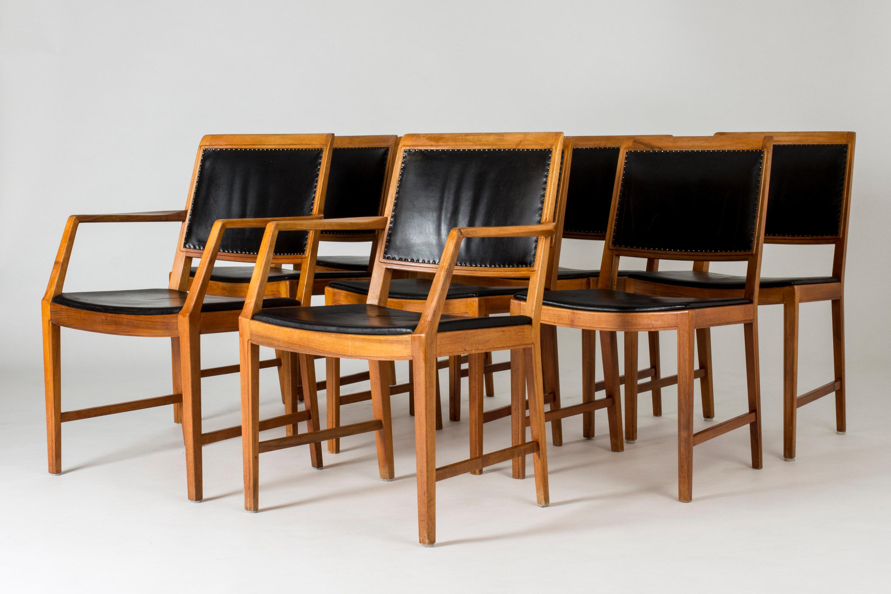 Set of eight elegant dining chairs by Bertil Fridhagen, two of them armchairs. Upholstered with black leather, attached with decorative nails on the backrests. Original leather with patina.