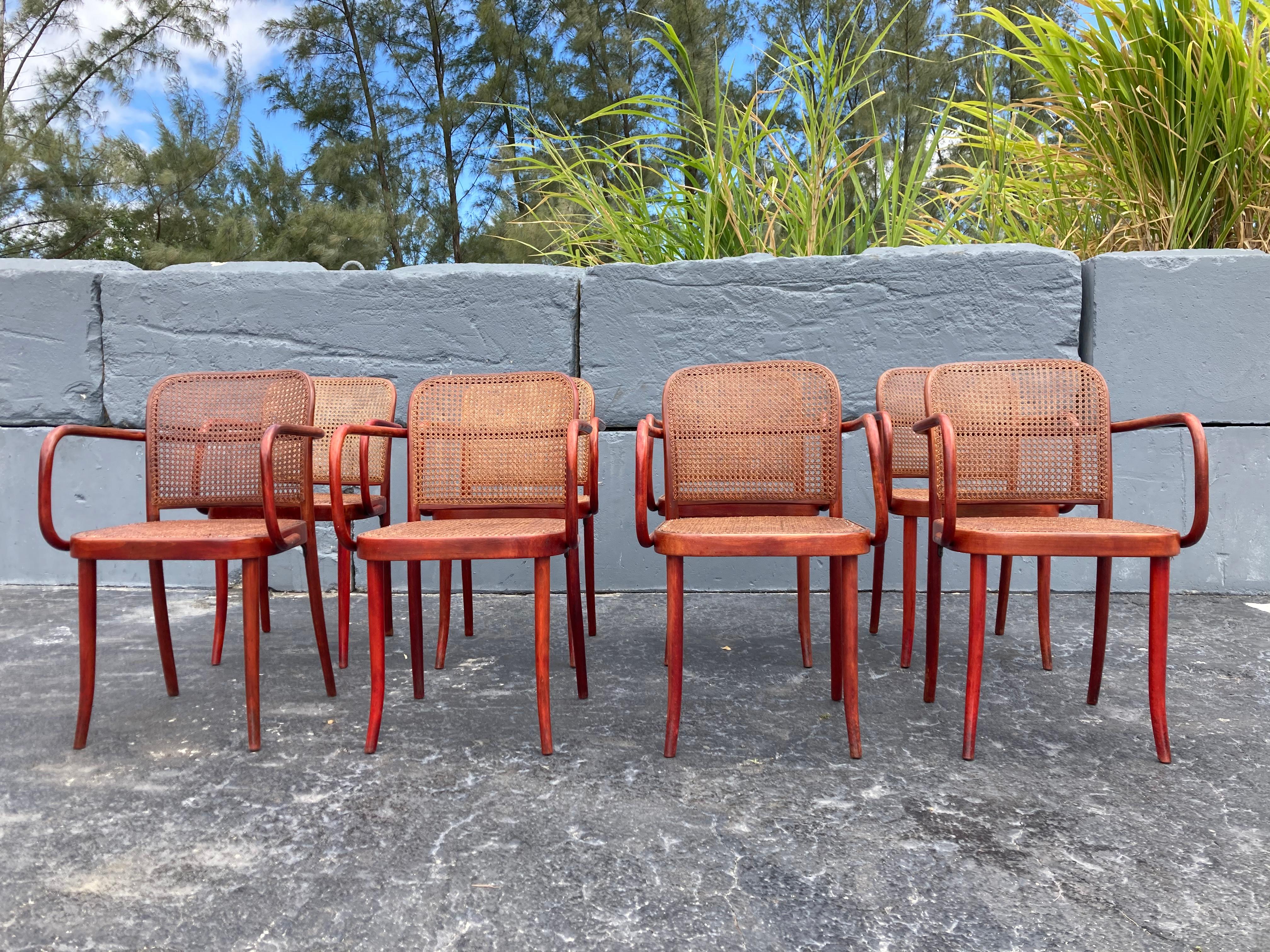 Beautiful rare set of eight Josef Hoffmann chairs in original red stain finish. Measures: Arm height is 27”.
Chairs have variations in color of wood and cane. Rich patina.