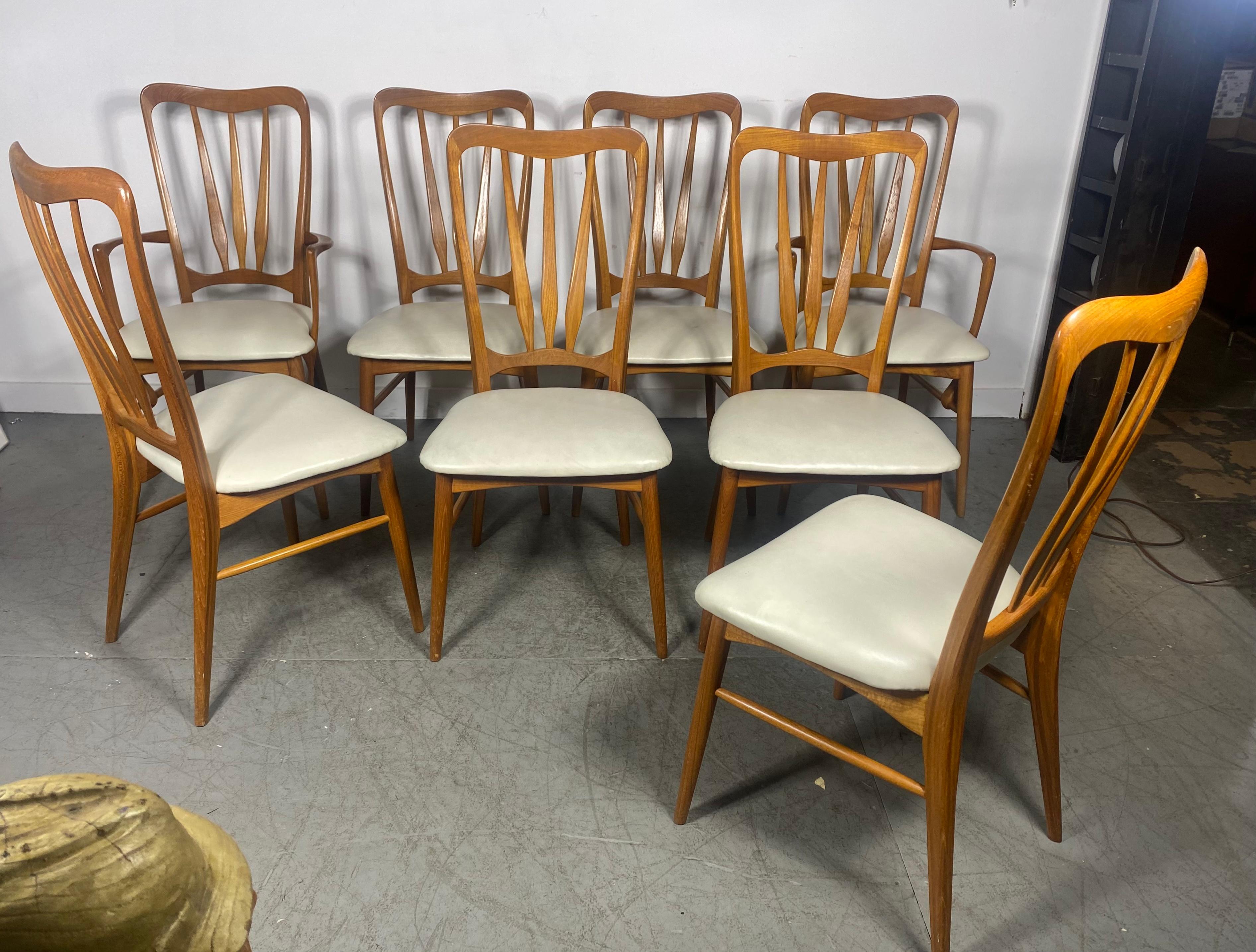 Set of eight Niels Koefoed “Ingrid” dining chairs in teak, c.1960s, Denmark for Koefoeds Hornslet. The set consists of six side chairs and two armchairs. All chairs feature sculpted frames with white Naugahyde on the seats. The armchairs have a