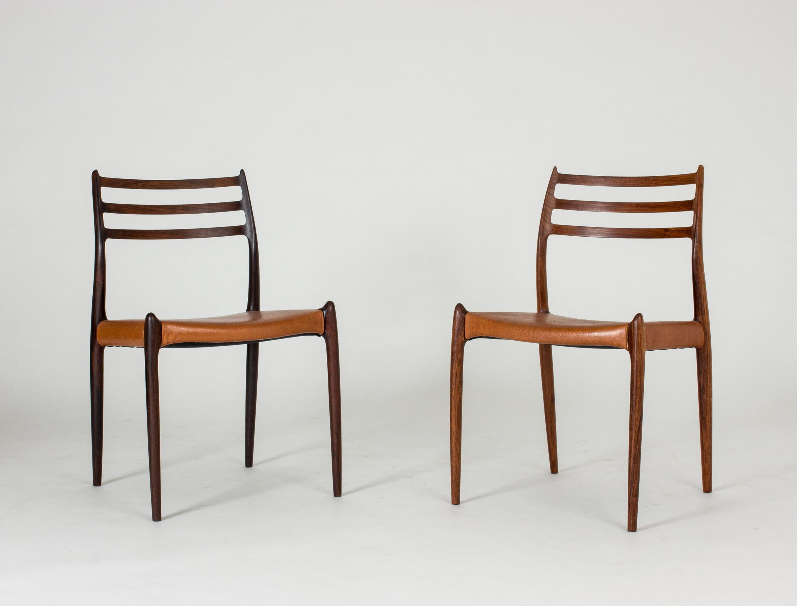 Set of eight gorgeous rosewood dining chairs by Niels O. Møller. Vintage leather seats in a tan nuance. The fluency of the design and the hornlike details at the seats and on the backrests give these chairs a breathtaking grace with daring