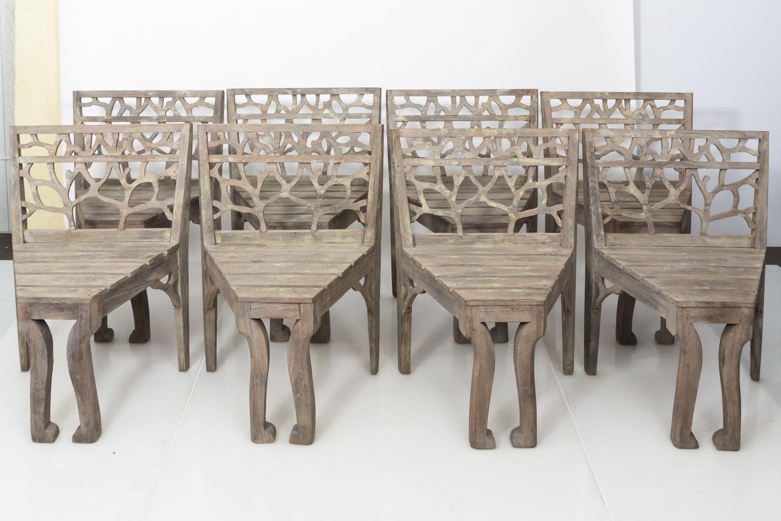 Set of four teak wood garden dining chairs with tree branch tracery on the seat back, circa 20th century.