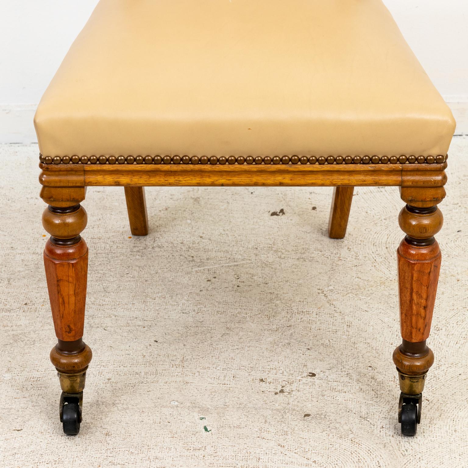 Circa 1990s Continental style set of eight painted and decorated dining chairs in leather with nail head trim, ball-and-ring turned legs, and castors from John Rosselli. Made in the United States. Please note of wear consistent with age.