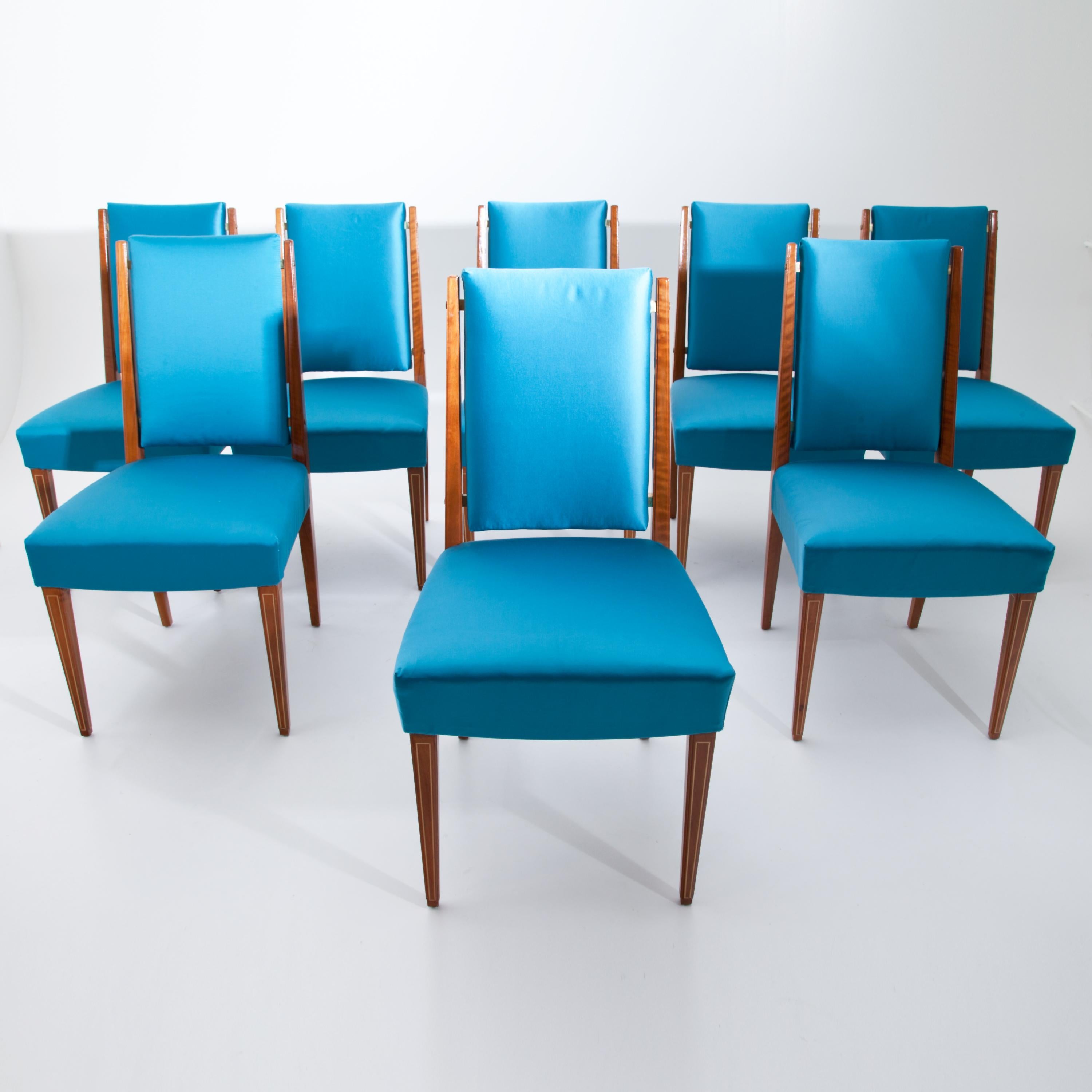 Set of eight dining room chairs with upholstered seats and backrests. The square pointed feet at the front are inlaid with brass threads. Very good, restored condition. The chairs were also newly covered with a high-quality blue fabric.