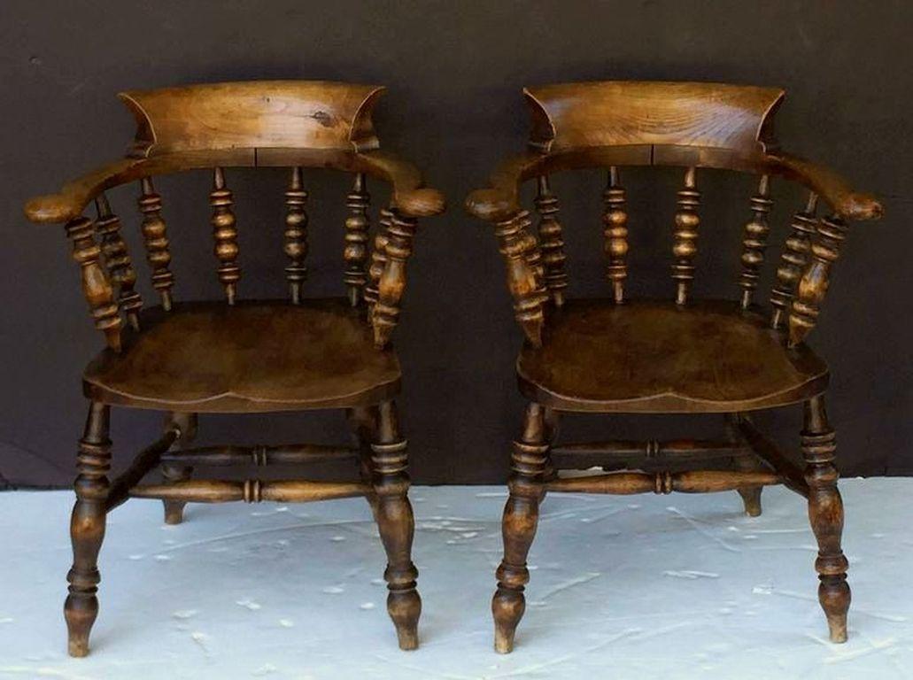 A fine set of eight large English bow armchairs (also known as captain's chairs or smoker's bow arm chairs) of elm, ash and oak, each chair featuring a bowed top rail with continuous arm on turned spindle back, a comfortable moulded seat, mounted to