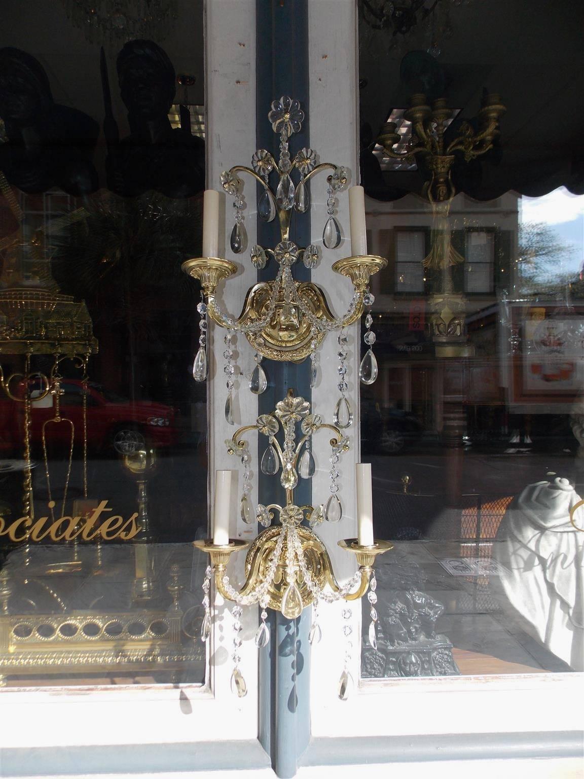 Set of Eight English brass and crystal two arm wall sconces with decorative floral and beading motif. Sconces were originally candle powered and have been electrified. Mid-19th century.