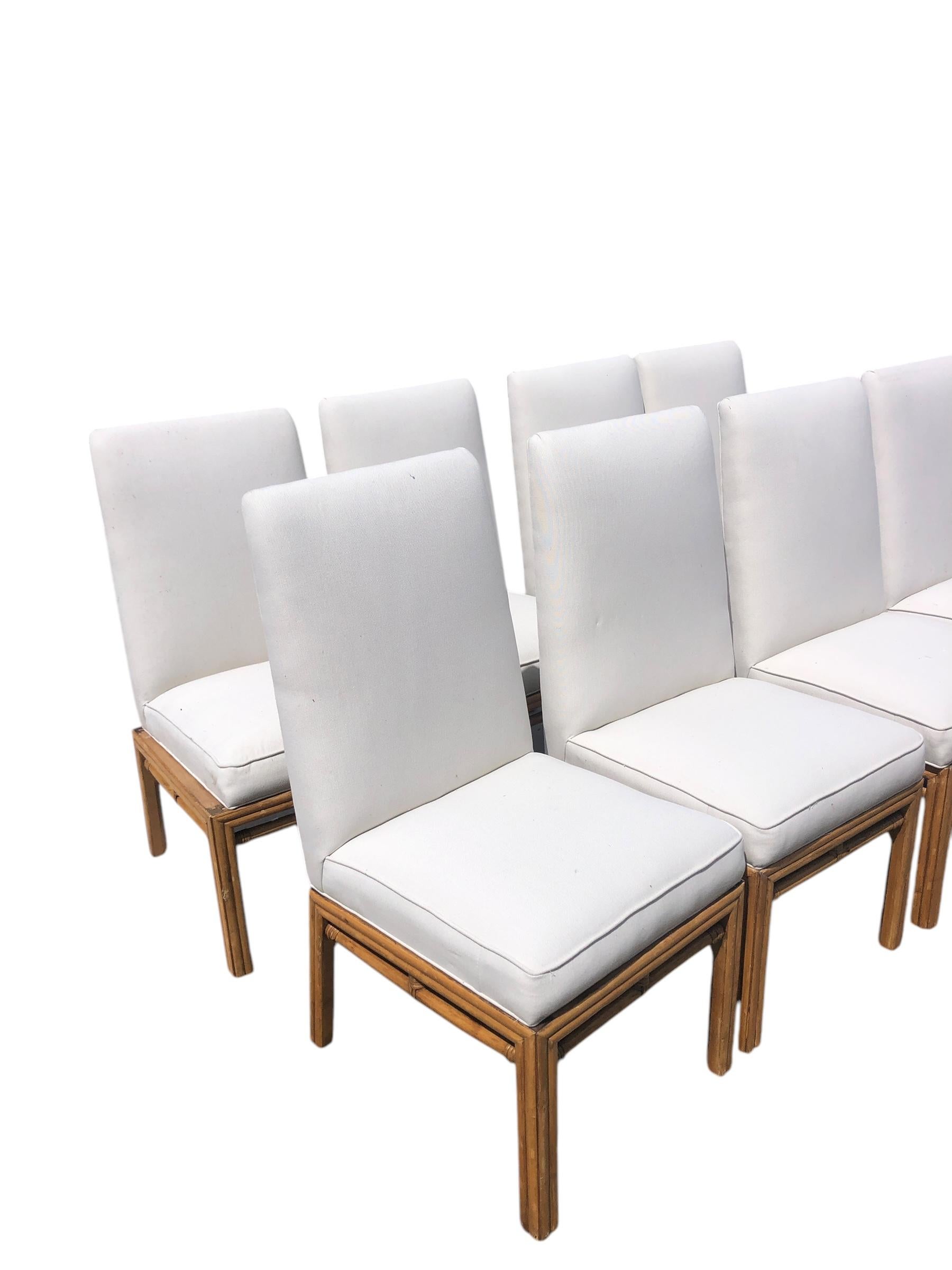 Set of Eight Ficks Reed Mid Century Rattan Upholstered Dining Chair. The fully upholstered seat and back sits atop a rattan frame. The chairs are newly upholstered in an off white linen fabric.
