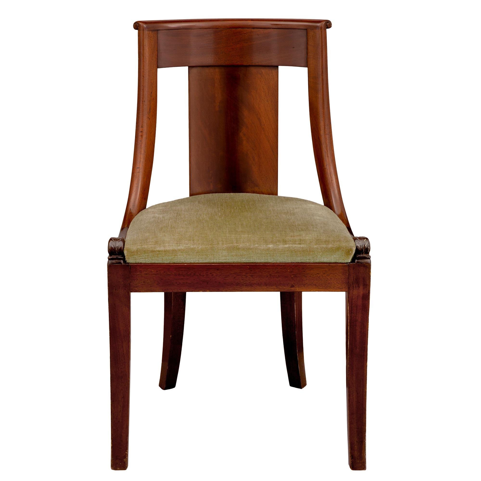 A most handsome set of eight French 19th century Empire style mahogany side/dining chairs. Each chair is raised by elegant slightly curved square tapered legs. Above the straight frieze are striking richly carved dolphins at either side of the