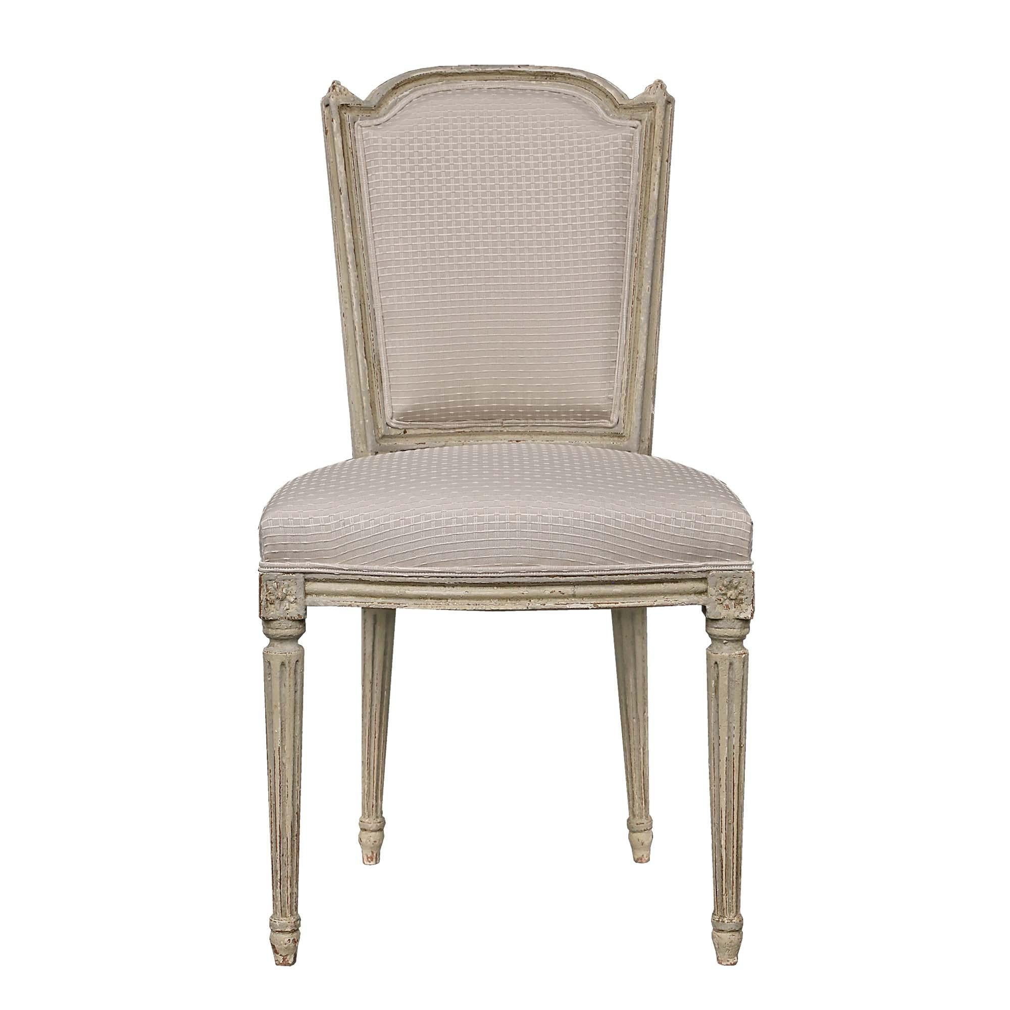 Elegante y completo juego de ocho sillas de comedor francesas del siglo XIX de estilo Luis XVI patinadas. Cada silla se eleva sobre patas cónicas circulares con un diseño estriado bajo rosetas de bloques. El friso recto muestra una banda moteada que