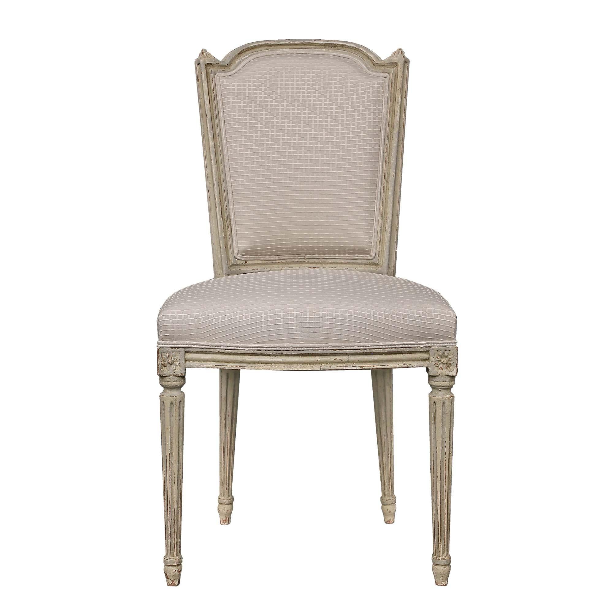 An elegant and complete set of eight French 19th century Louis XVI st. patinated dining chairs. Each chair is raised by circular tapered legs with a fluted design below block rosettes. The straight frieze displays a mottled band also framing the