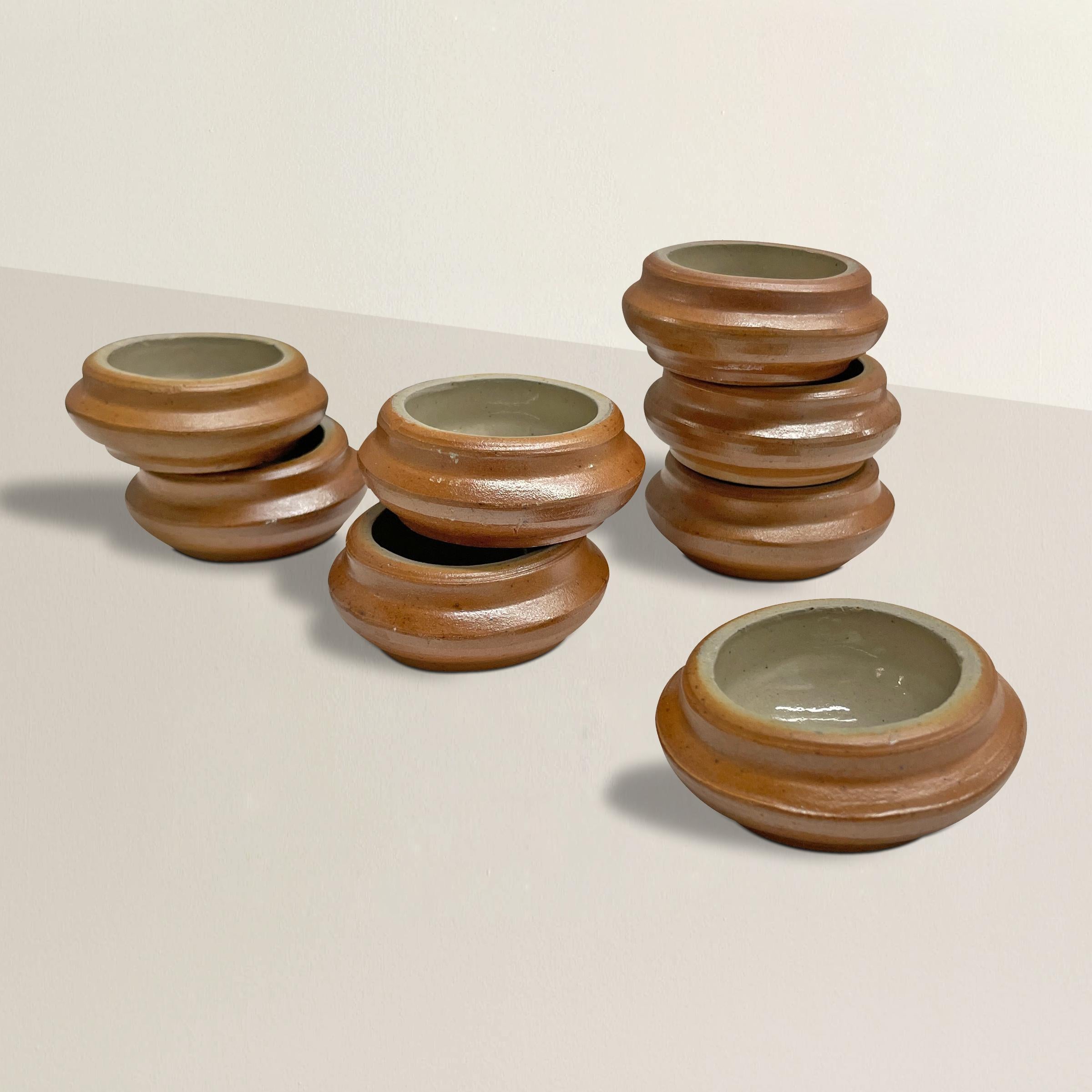 A wonderful set of eight early 20th century French ceramic salt cellars with a terracotta colored exterior and a shiny glazed interior. Perfect for salt at your next garden party, or for your mise en place in your home kitchen, filled with spices