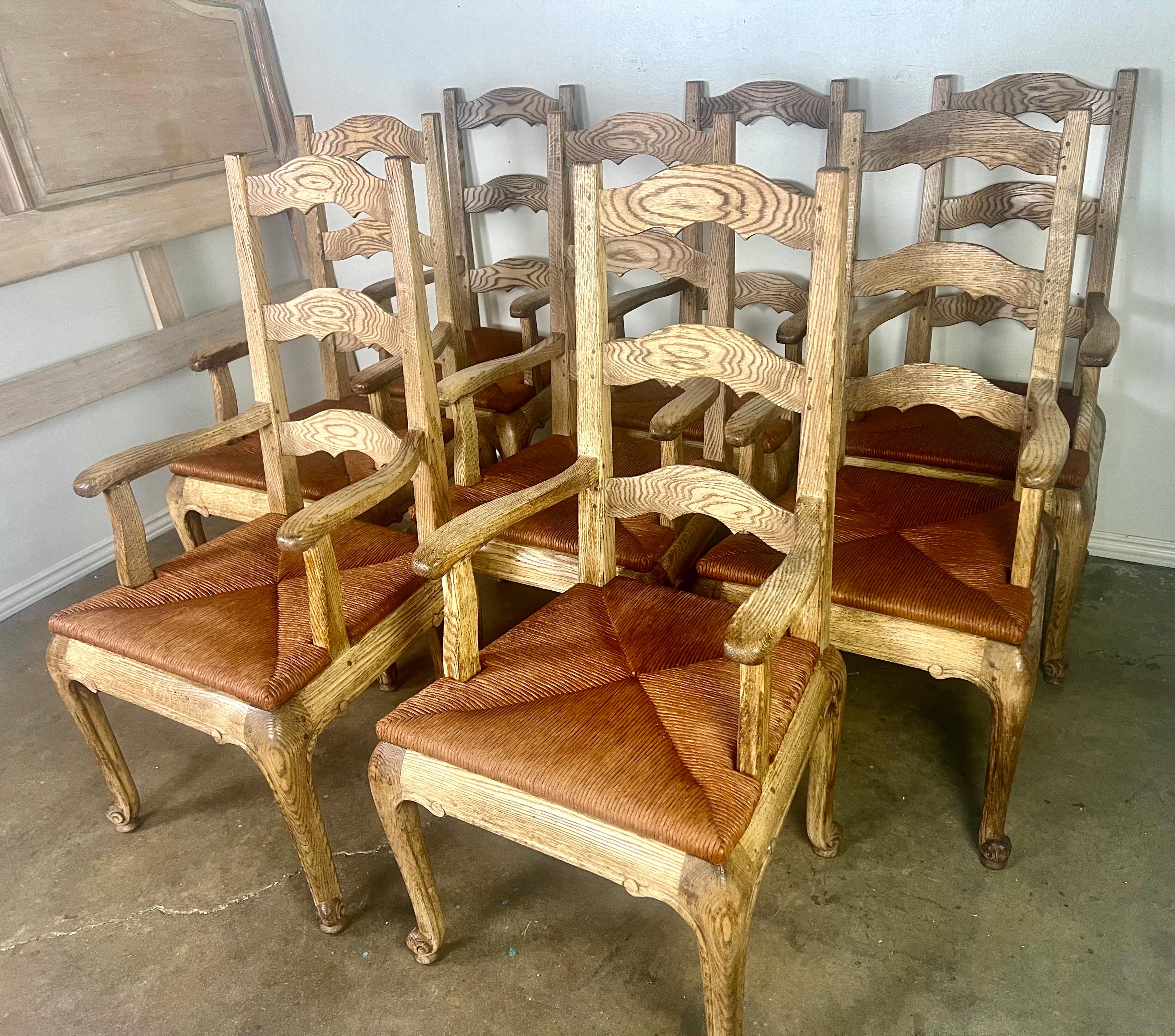 Set of eight French Provincial Ladderback armchairs with rush seats, crafted by Le Monde du Bois, a French furniture manufacturer in the early 1900's.  These chairs beautifully capture the rustic elegance and refined craftsmanship of early 20th