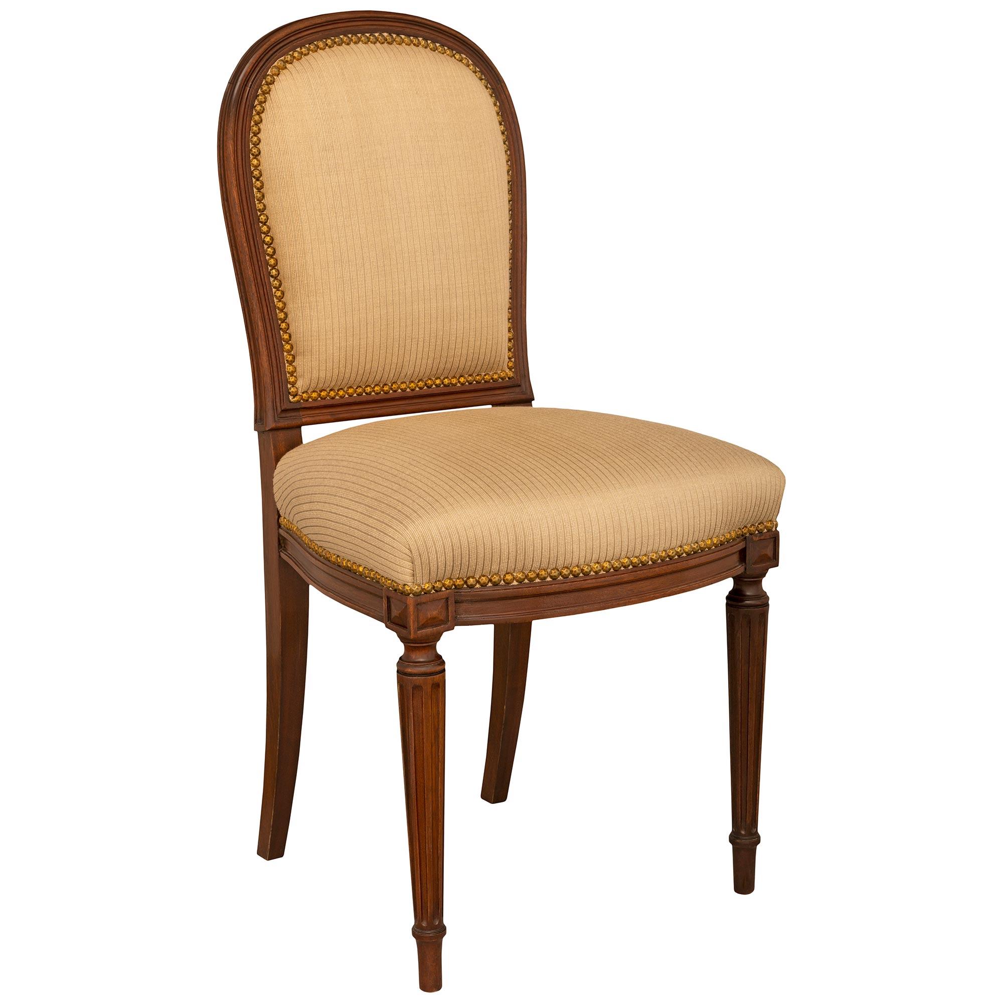 Ein Satz von acht französischen Beistellstühlen aus massivem Mahagoni des späten 19. Jahrhunderts. Die Garnitur wird von eleganten, konisch zulaufenden, kannelierten Beinen getragen. Darüber befindet sich ein profilierter Fries, der sich auf der