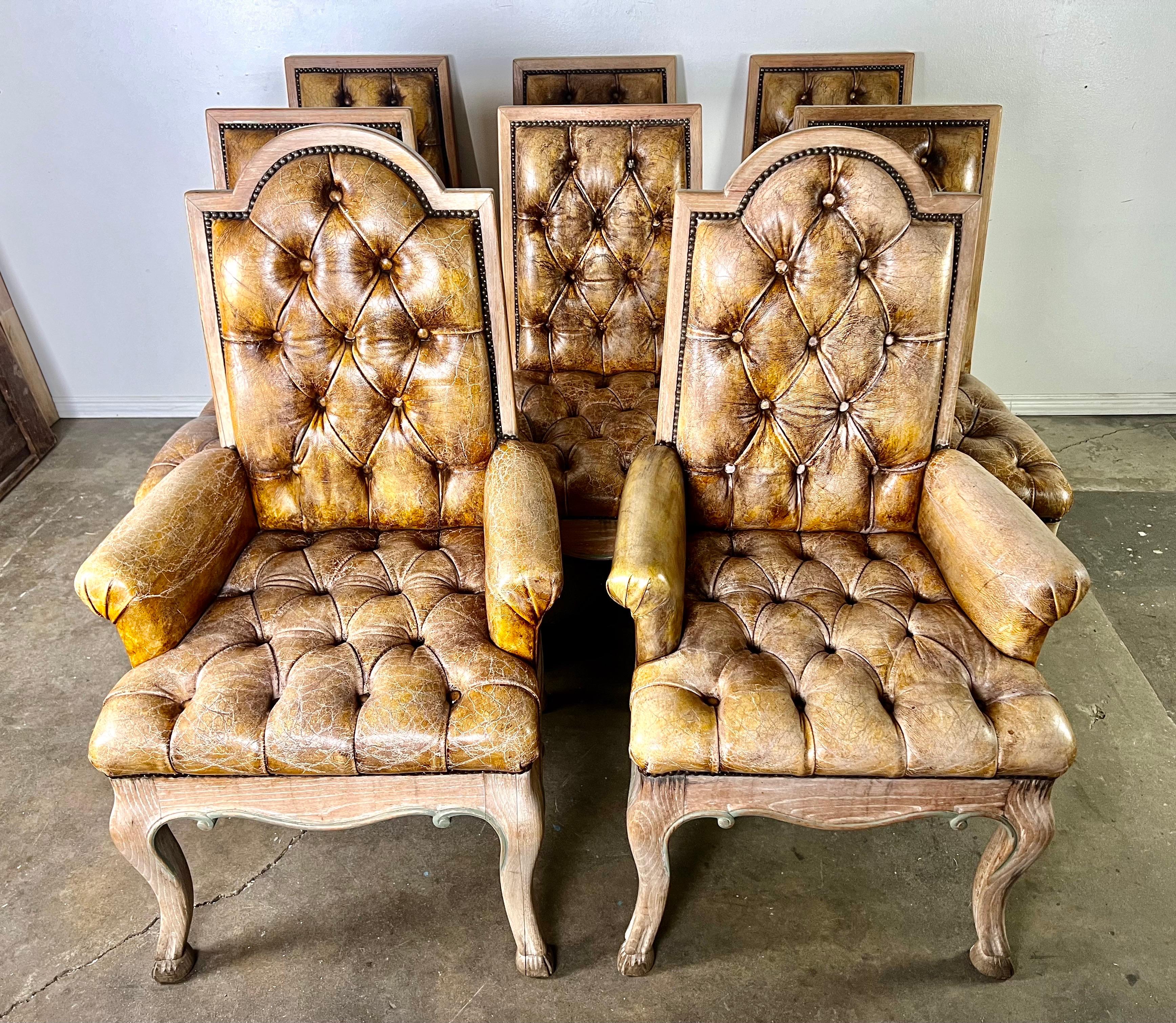 Set of eight French Provincial style dining chairs, featuring two armchairs and six side chairs upholstered in distressed tufted leather with nailhead trim detail.  The chairs stand on elegant cabriole legs with hoofed feet.

Armchair size-26