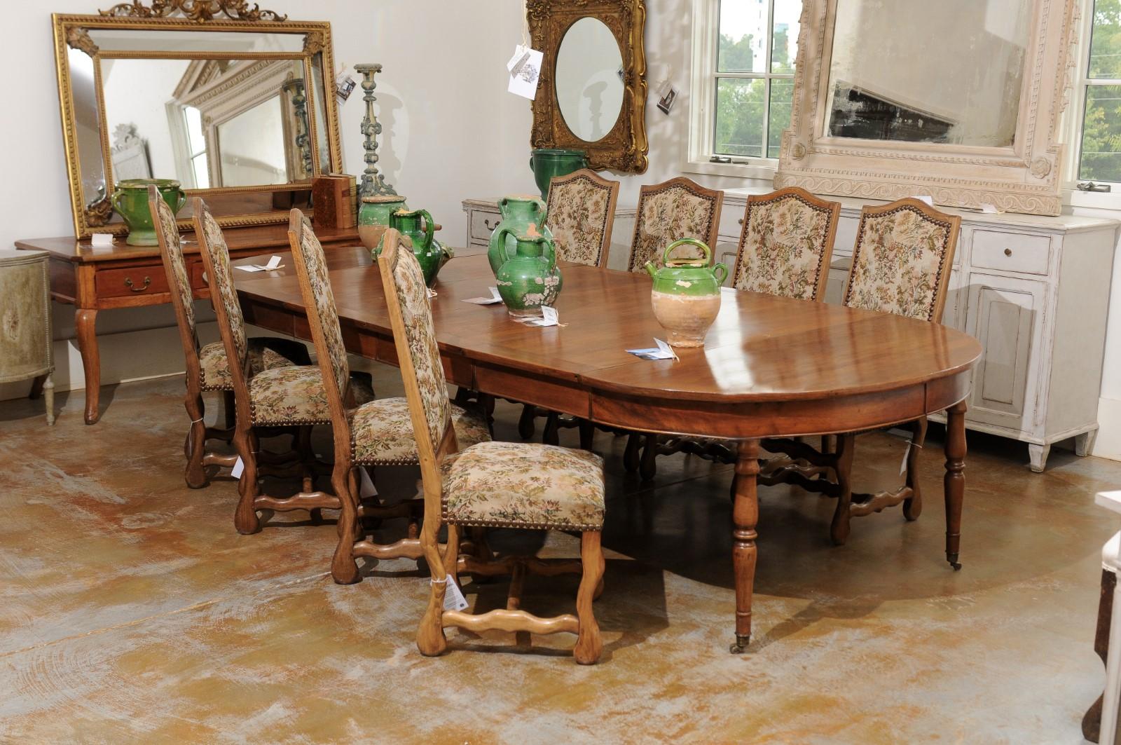 A set of eight French Louis XIII style os de mouton dining room side chairs from the 19th century with tapestry upholstery and nailhead trim. Born in France during the 19th century, this set of dining room chairs presents the stylistic