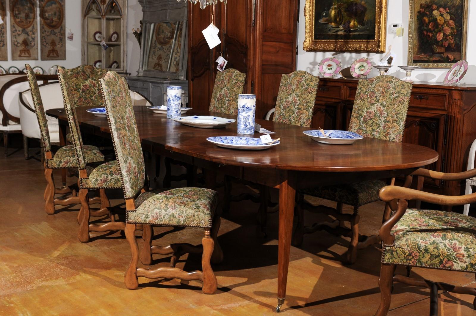 A set of eight French Louis XIII style os de mouton dining chairs from the 19th century with tapestry upholstery, made of six sides and two arms. Born in France during the 19th century, this set of dining chairs presents the stylistic