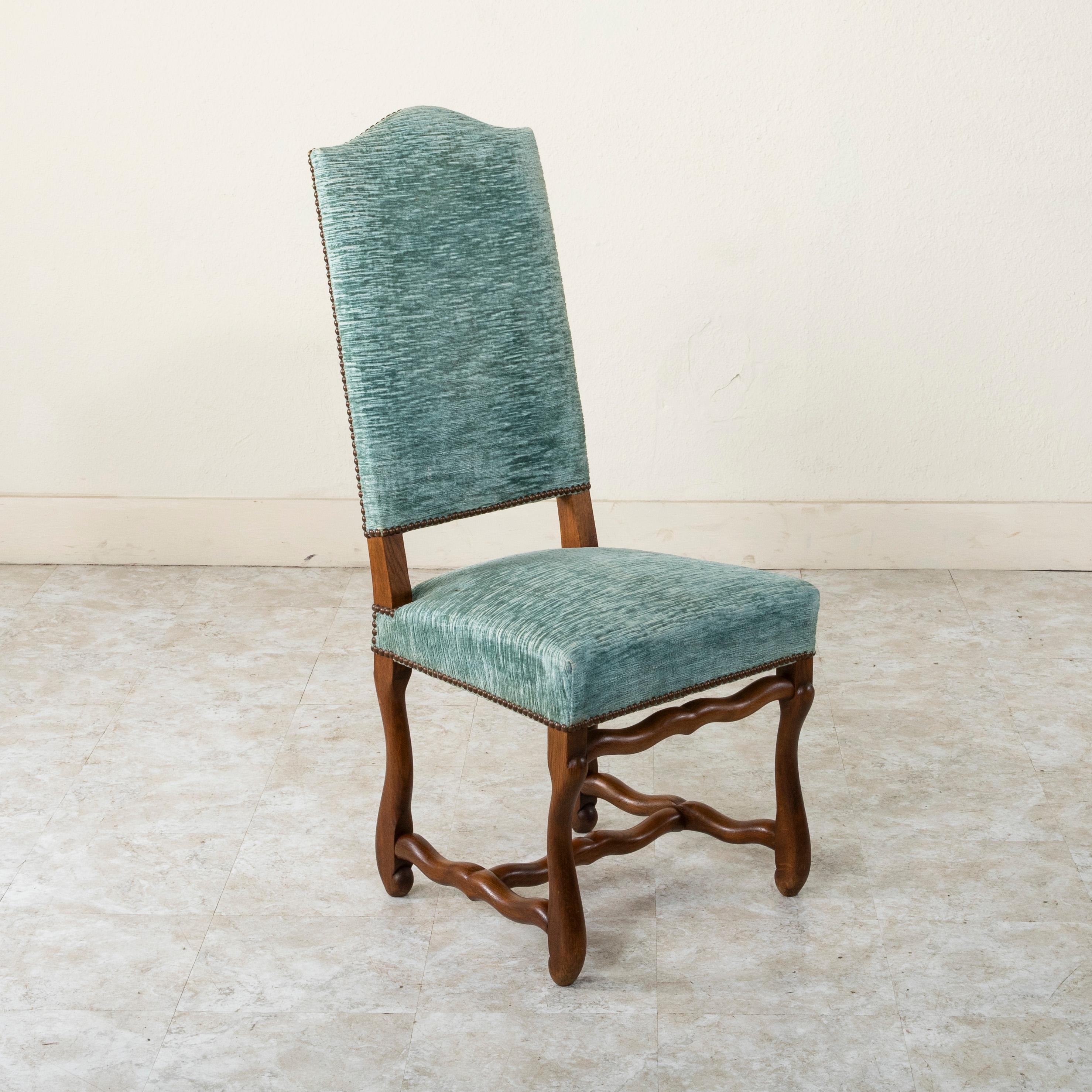 This set of eight French oak mutton leg side chairs or dining chairs from the mid-twentieth century are of hand pegged construction. These tall dining chairs with arched backs are upholstered in a blue mohair and finished with nail head trim. The