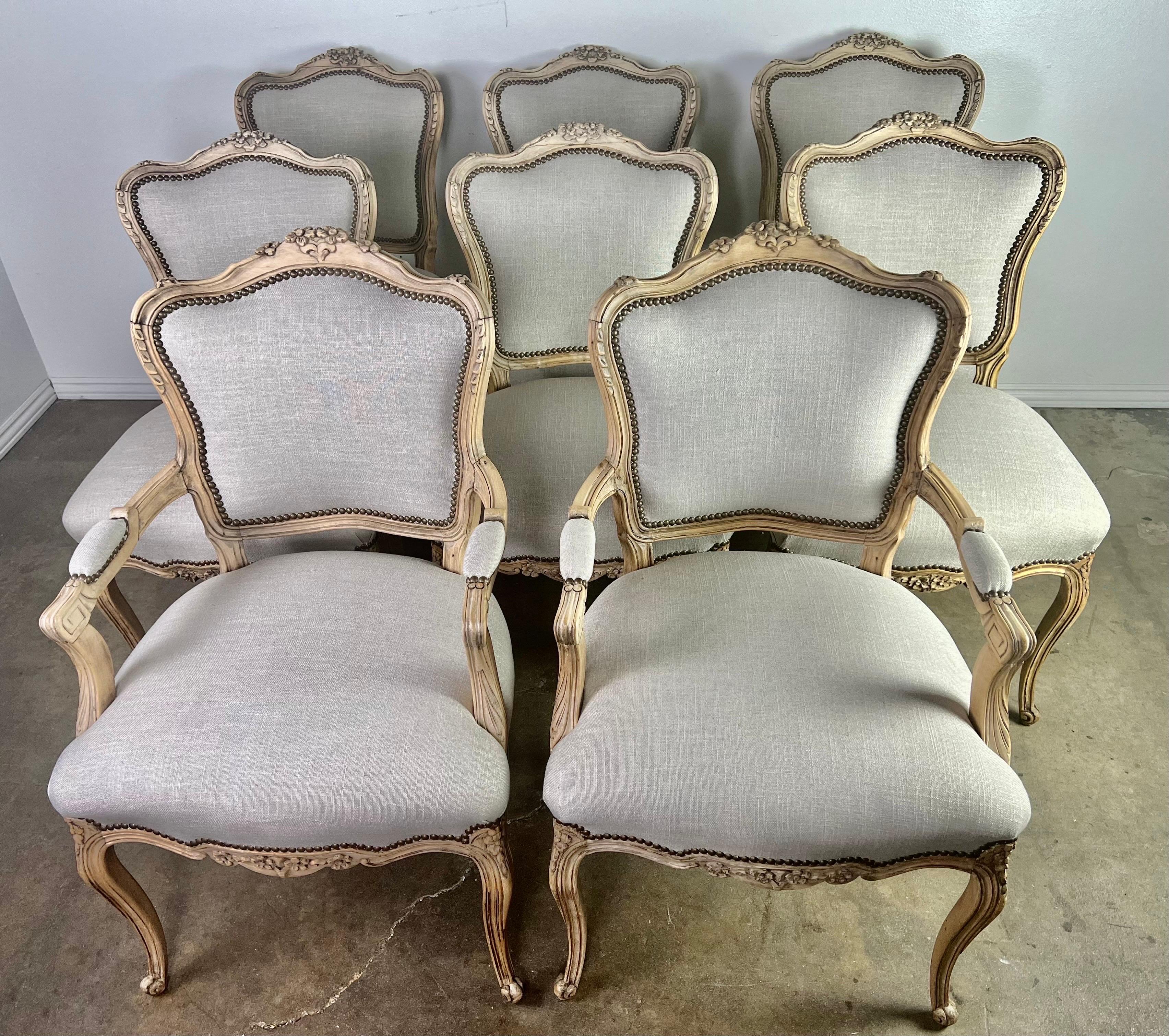 Set of eight French Louis XV style dining chairs. The chairs stand on four cabriole legs with rams head feet. There are carved flowers on the top of the chair frame. The chairs are newly upholstered in linen with nailhead trim detail.

Size side