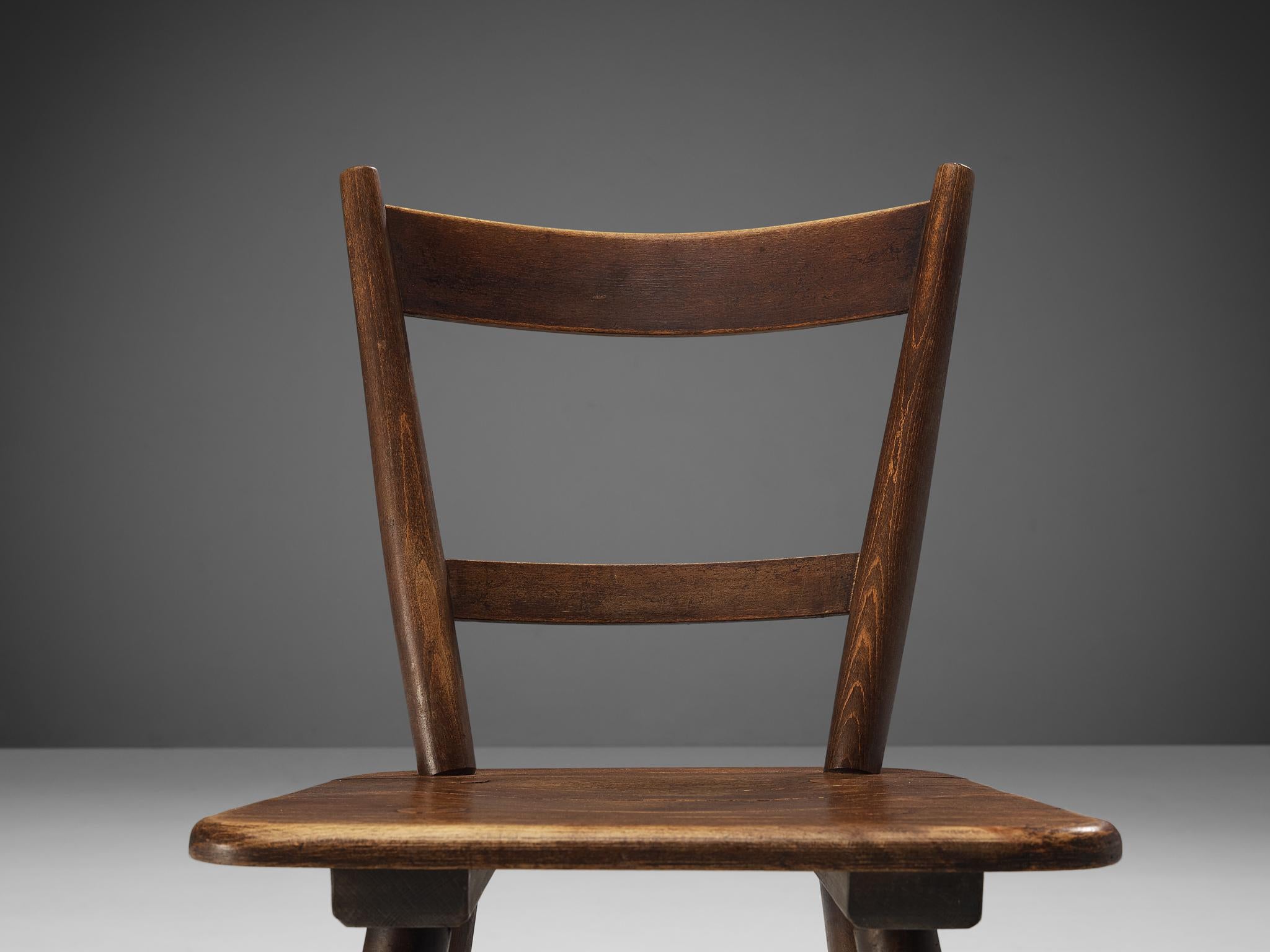Dining chairs, stained wood, France, late 1940s. 

Set of rustic dining chairs manufactured in France. Simple yet stylish, these chairs feature a modest frame with sleek, elegant elements. Note for example the tapered legs slightly pointing