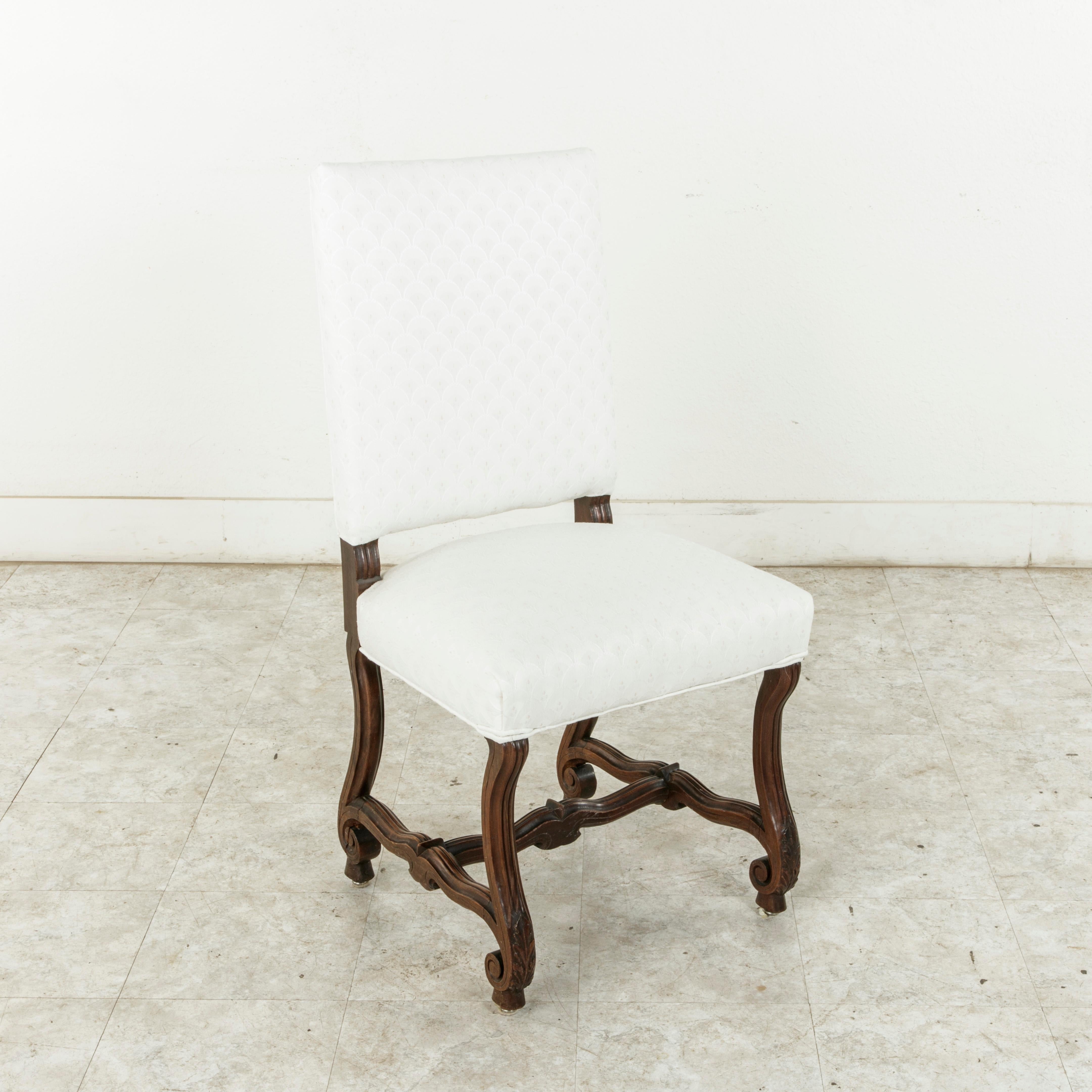 This set of eight French walnut side chairs or dining chairs from the turn of the 20th century features sturdy fluted mutton legs with scrolled feet. The legs are joined by a fluted H stretched that provides additional stability. Newly upholstered