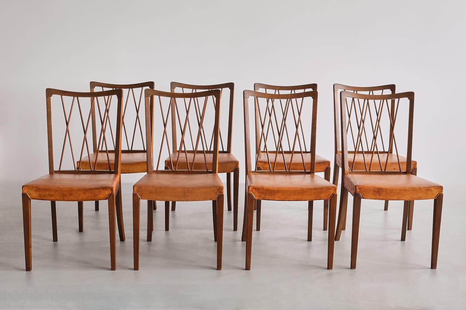 This very rare set of eight dining chairs was designed by Frode Holm and produced by Illum Bolighus in Denmark in the 1940s. 
The elegant design is marked by the tapered front legs, the slightly curved back legs and the distinct back rest. The