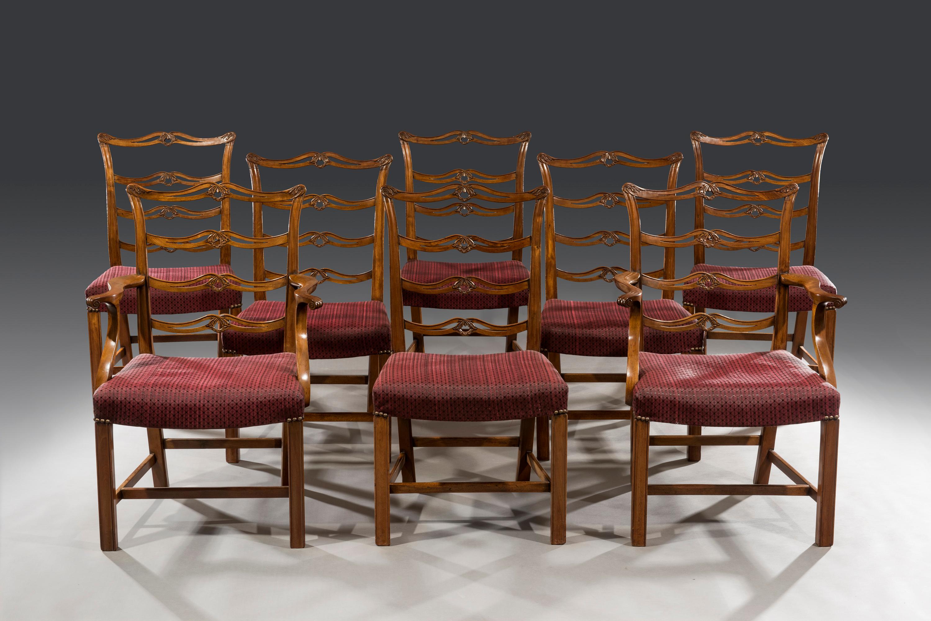 The set of eight carved mahogany dining chairs with saddle seats have recently been recovered in fine horse-hair upholstery. The ladder- back chairs have horizontal cross rails and are decorated with pierced interlacing centres and carved ears to
