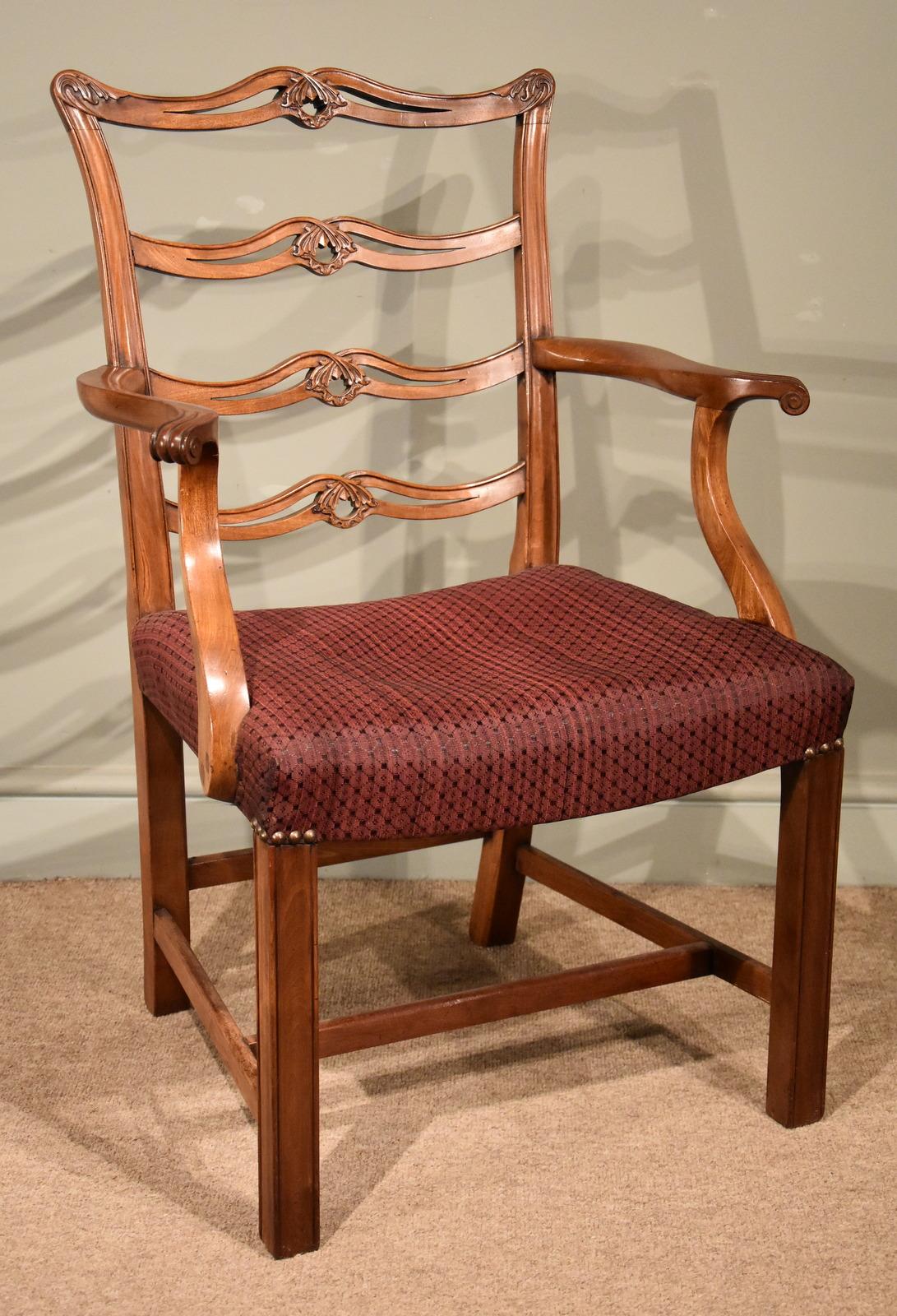 The set of eight (6 + 2) carved mahogany dining chairs with saddle seats have recently been recovered in fine horse hair upholstery. The ladderback chairs have horizontal cross rails and are decorated with pierced interlacing centres and carved ears