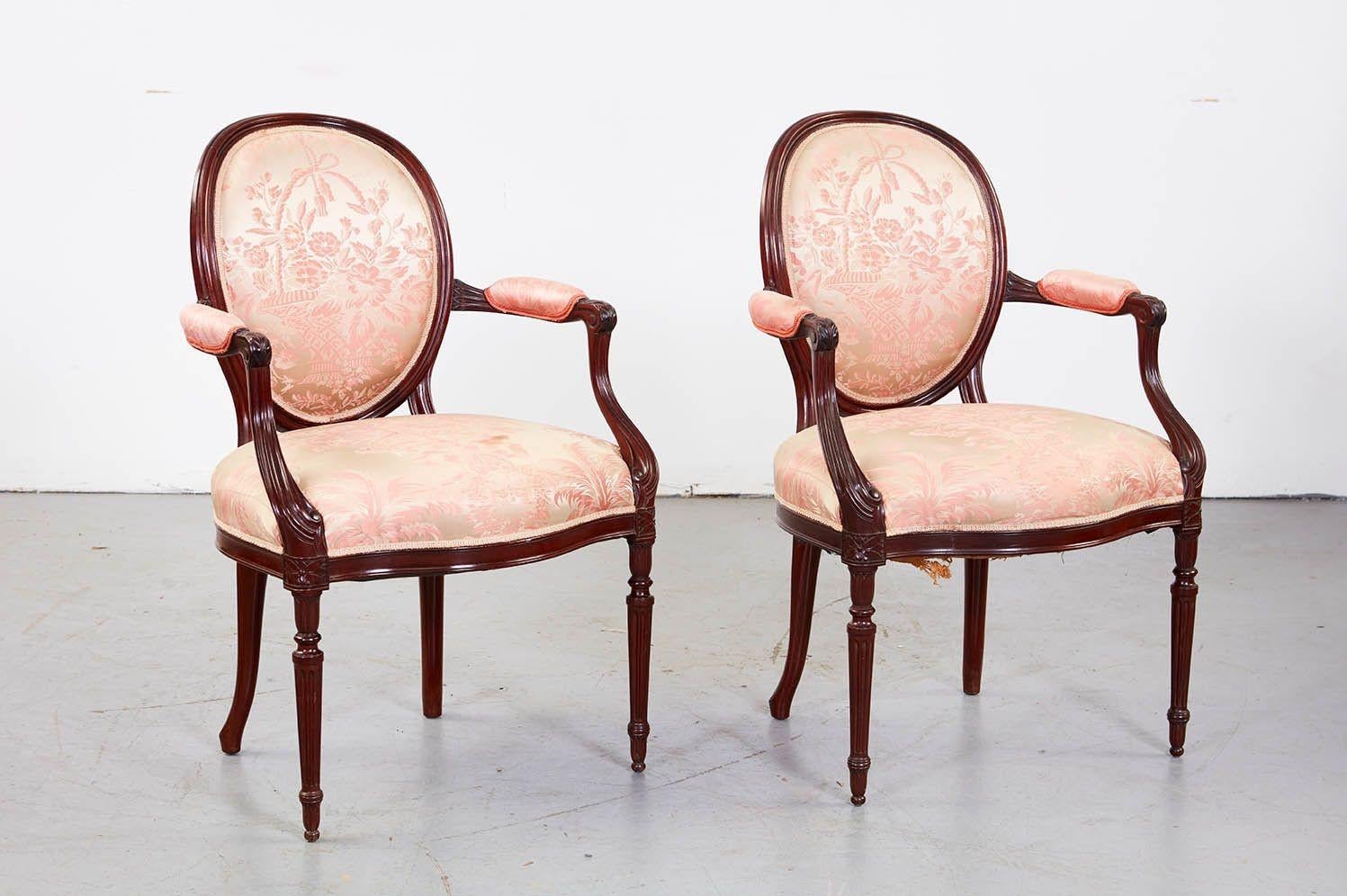 Fine set of eight George III mahogany oval back armchairs with upholstered backs, armrests and seat, the arms with scroll ends and long leaf details, the apron finally molded and standing on turned and carved legs.  England circa 1900.