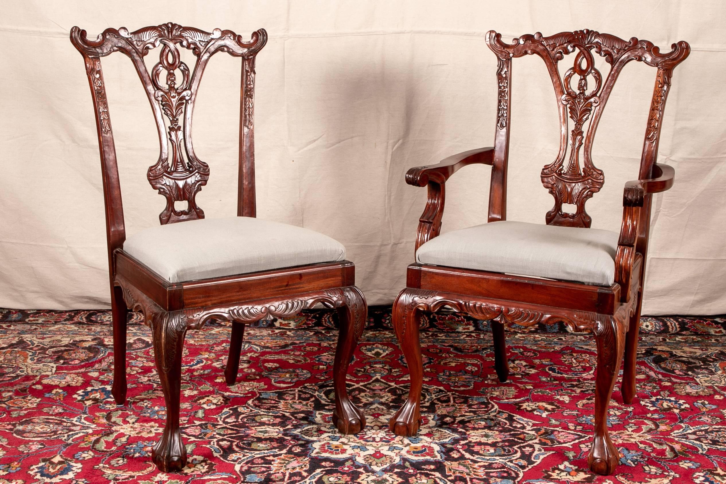 Set of eight Georgian style carved mahogany dining chairs, two arm and six side chairs. Carved mahogany with leafy scrolled crest rails, openwork leafy splats, and carved leafy seat frames. Raised on cabriole legs in front with carved acanthus leaf