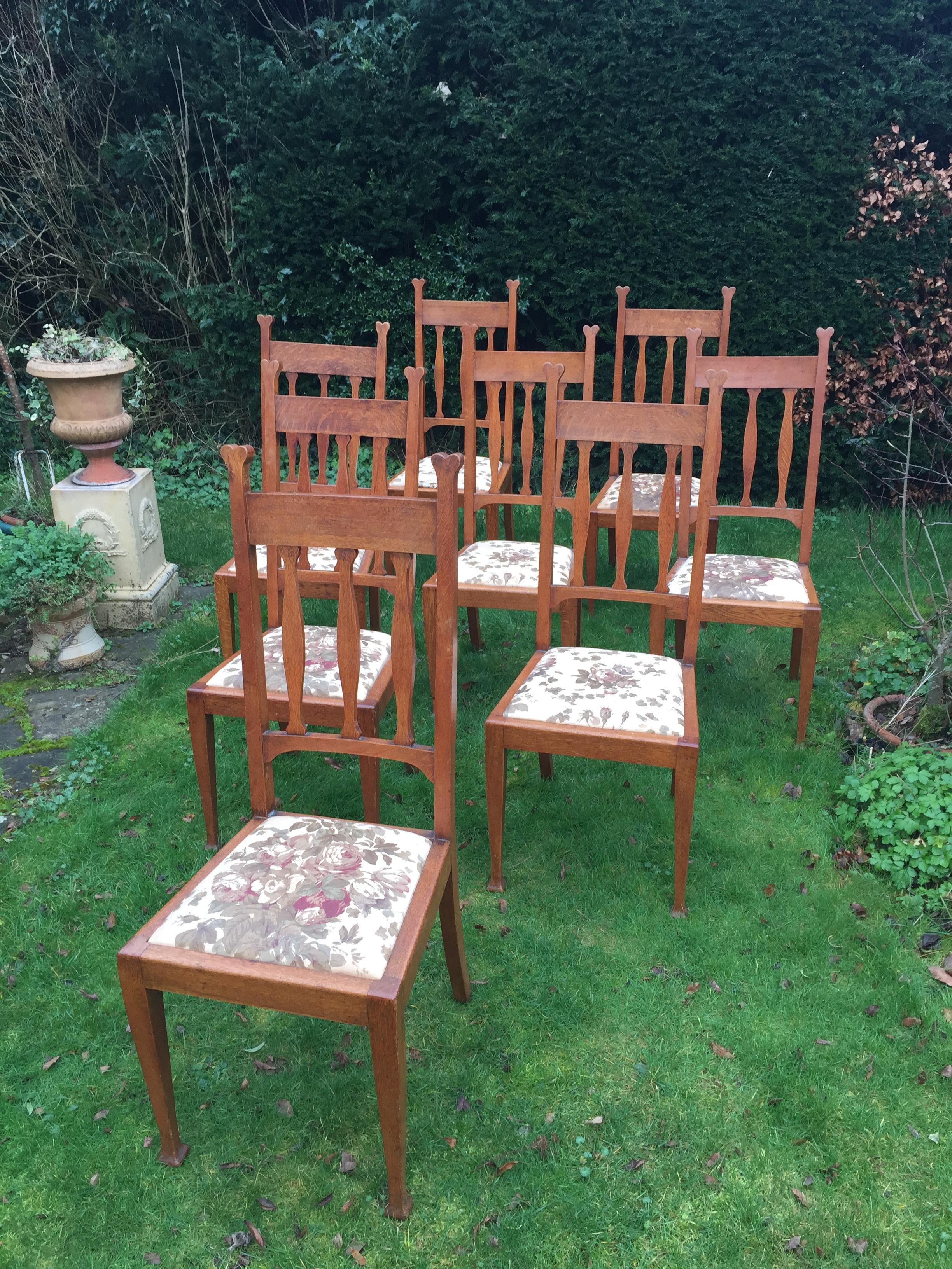 From the furnishers of the Royal Yacht, Cunard liners and top London hotels an extremely elegant set of eight high back dining chairs from the Arts & Crafts period. Made of golden oak the uprights terminating in a heart motif, the backs with three