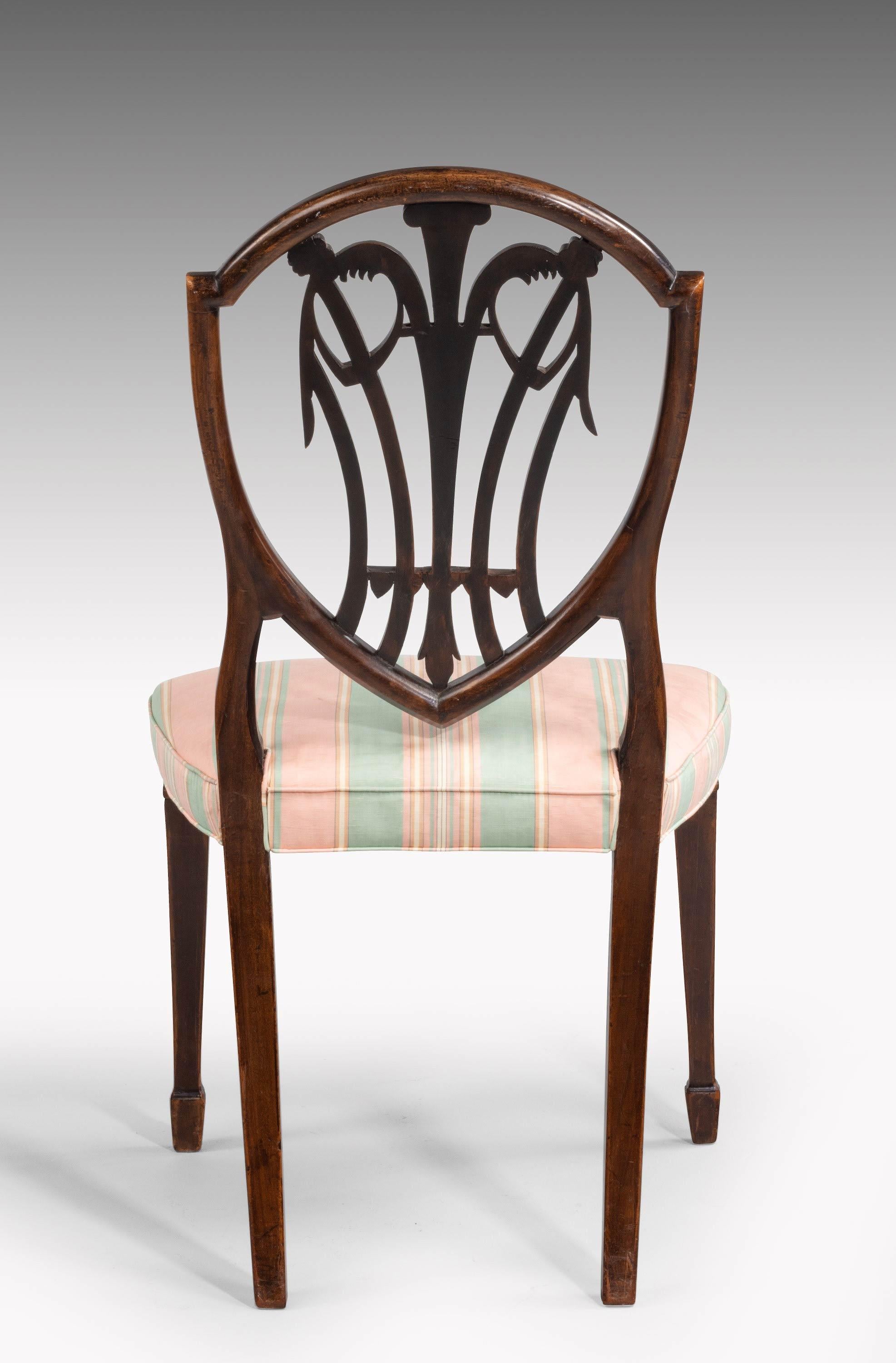 An extremely elegant set of eight mahogany chairs of typical Hepplewhite design. The shield shaped backs incorporating beautifully carved Prince of Wales feathers and descending bell flowers. The carvings of quite exceptional quality. 

Seat